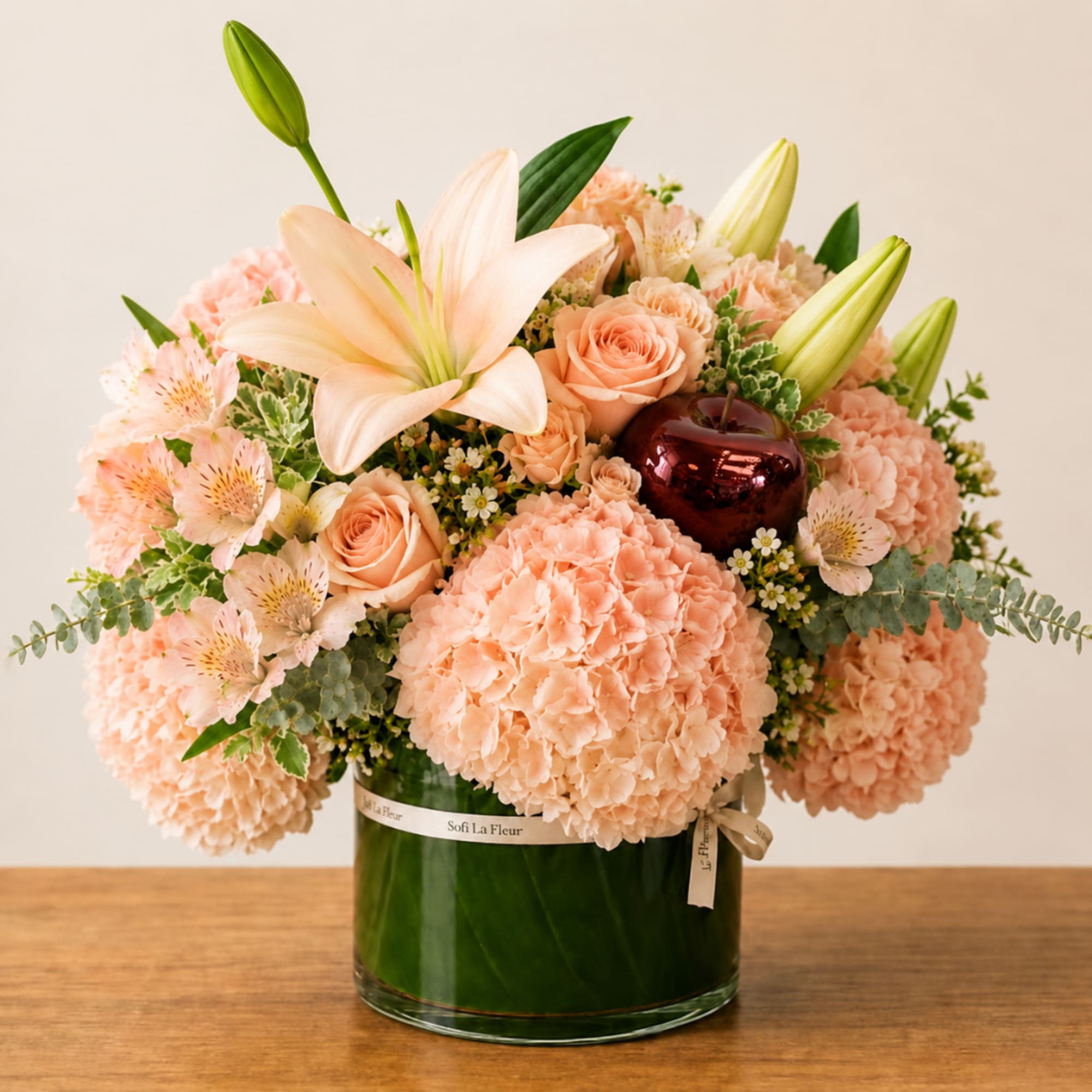 Peach bouquet with lilies, roses, and hydrangeas in a glass vase