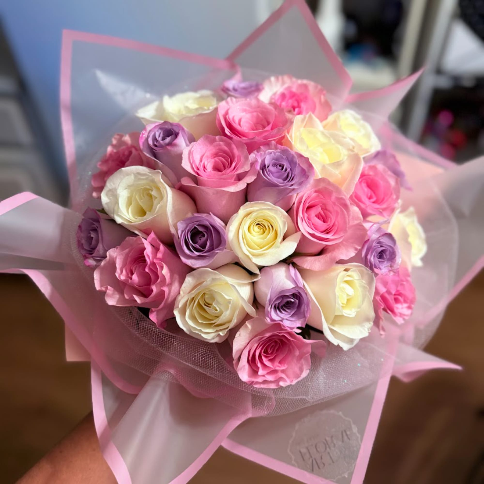 Bouquet of pink, white, and lavender roses wrapped in pink paper