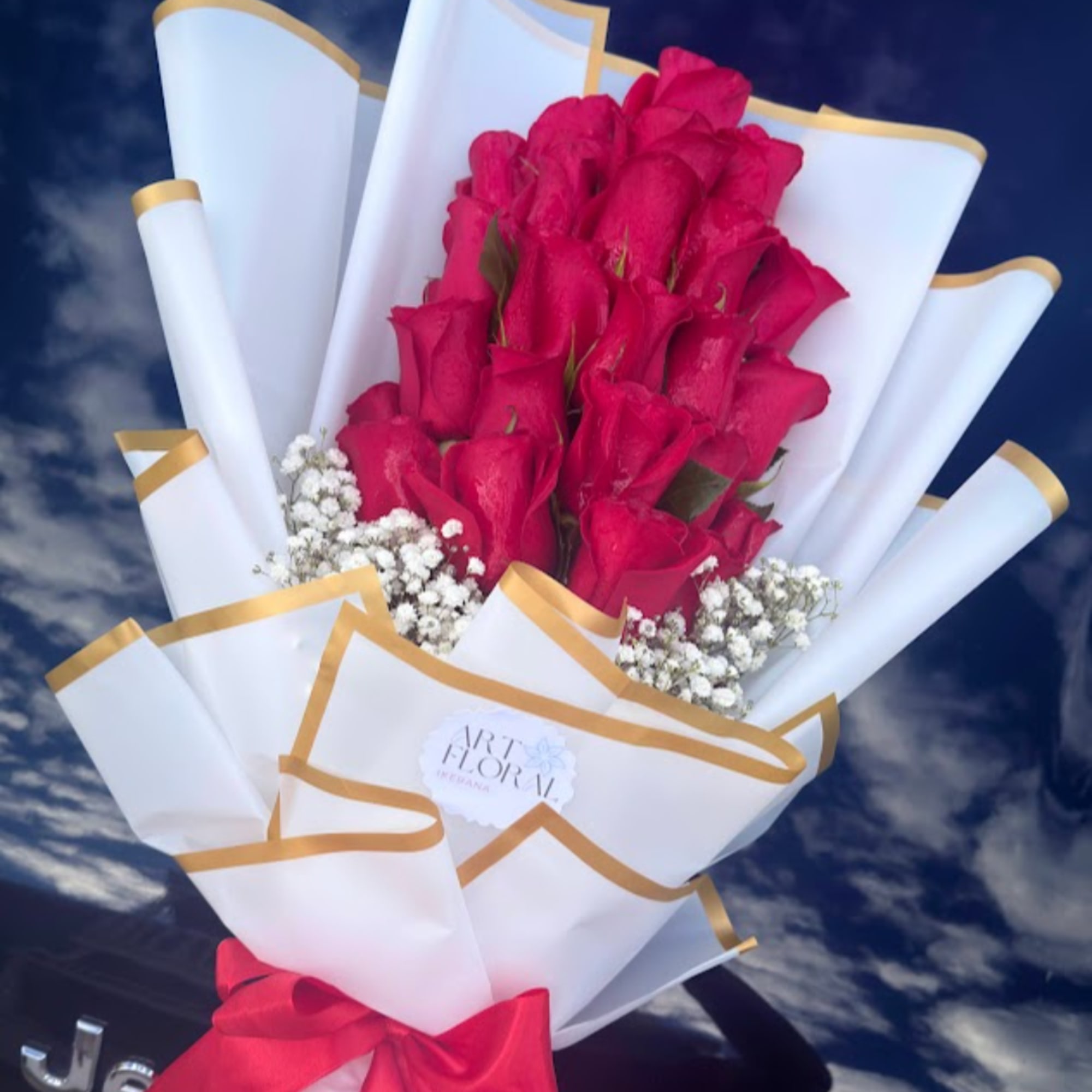 Bouquet of hot pink roses wrapped in white paper with gold trim