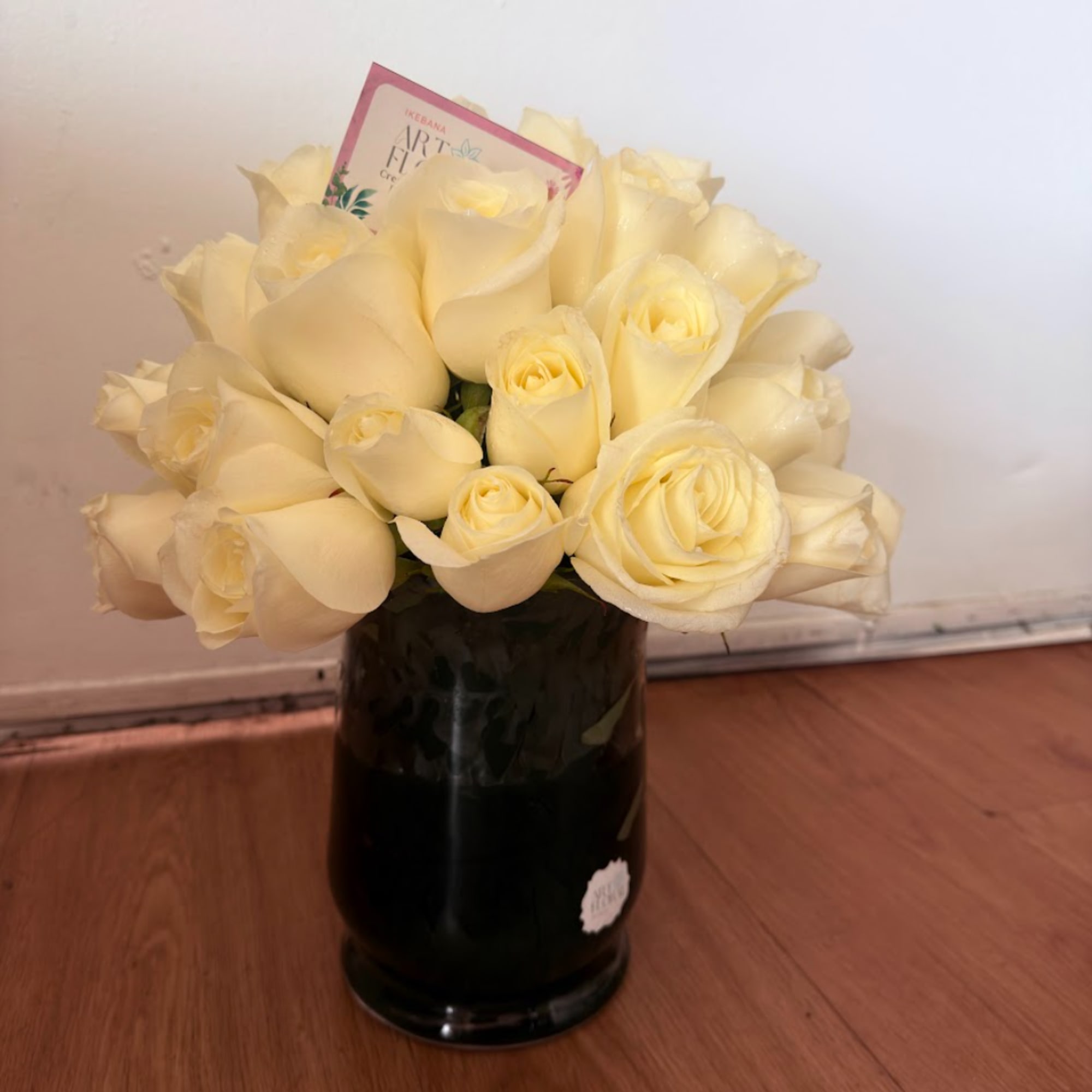 Bouquet of cream roses in a dark glass vase