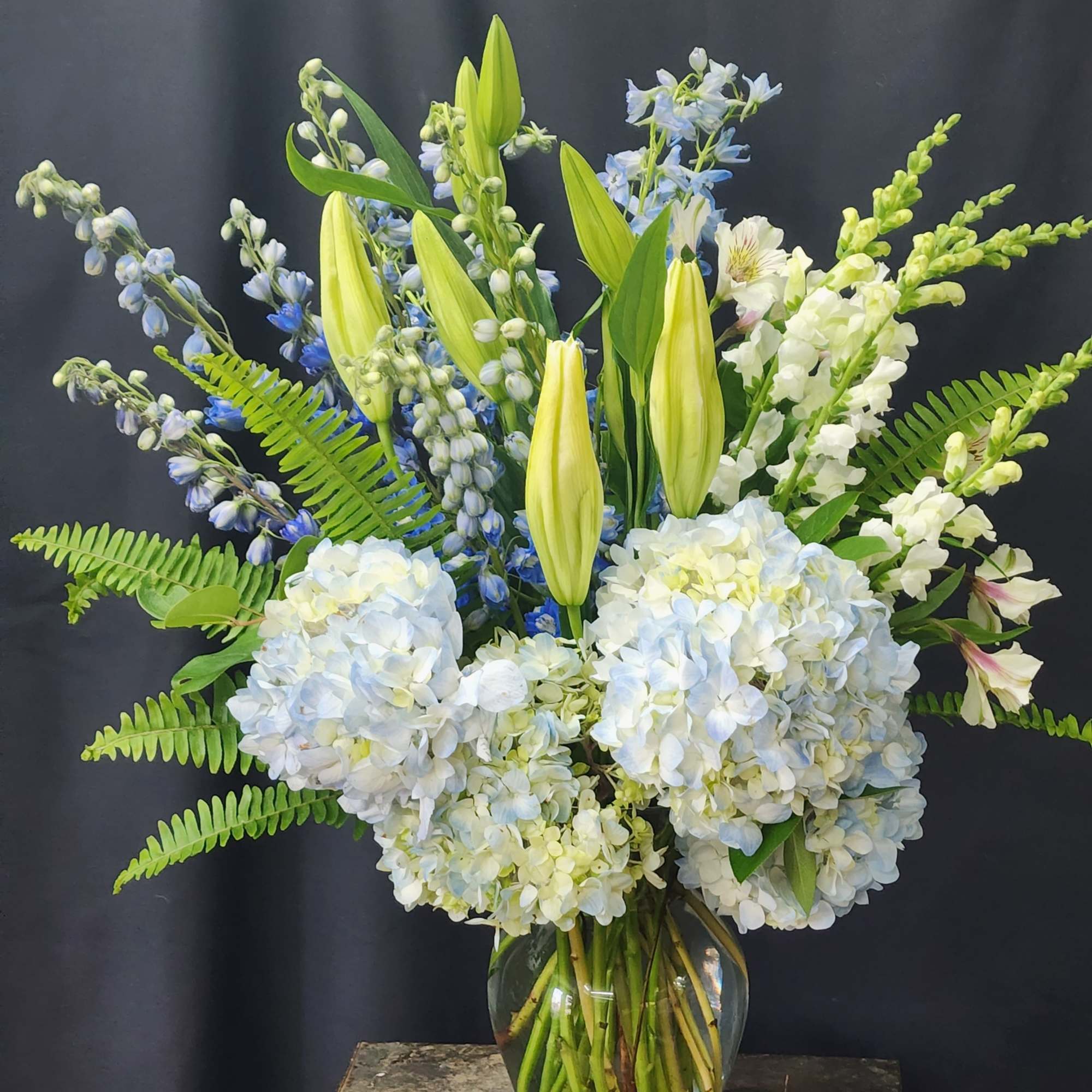 Blue and white floral arrangement with lilies and hydrangeas in a glass vase