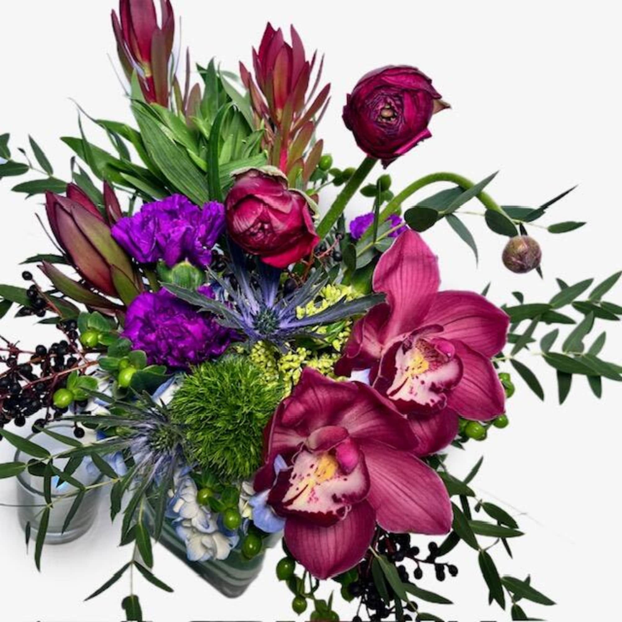 Bouquet of magenta orchids and purple flowers in a glass vase