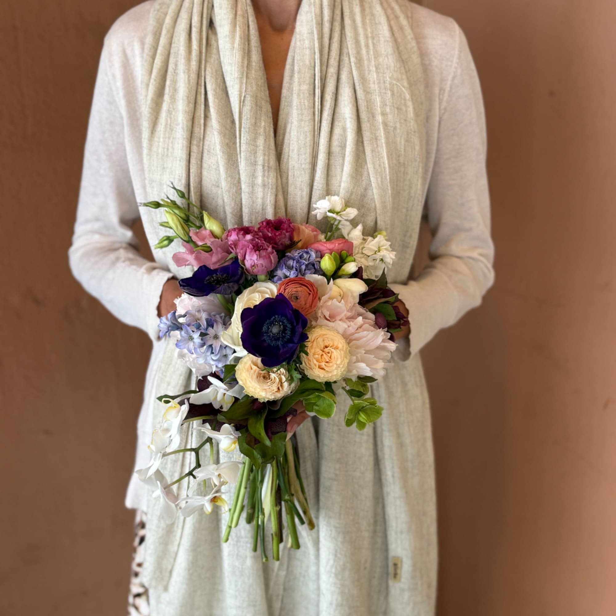 Person holding a colorful bridal bouquet with mixed flowers