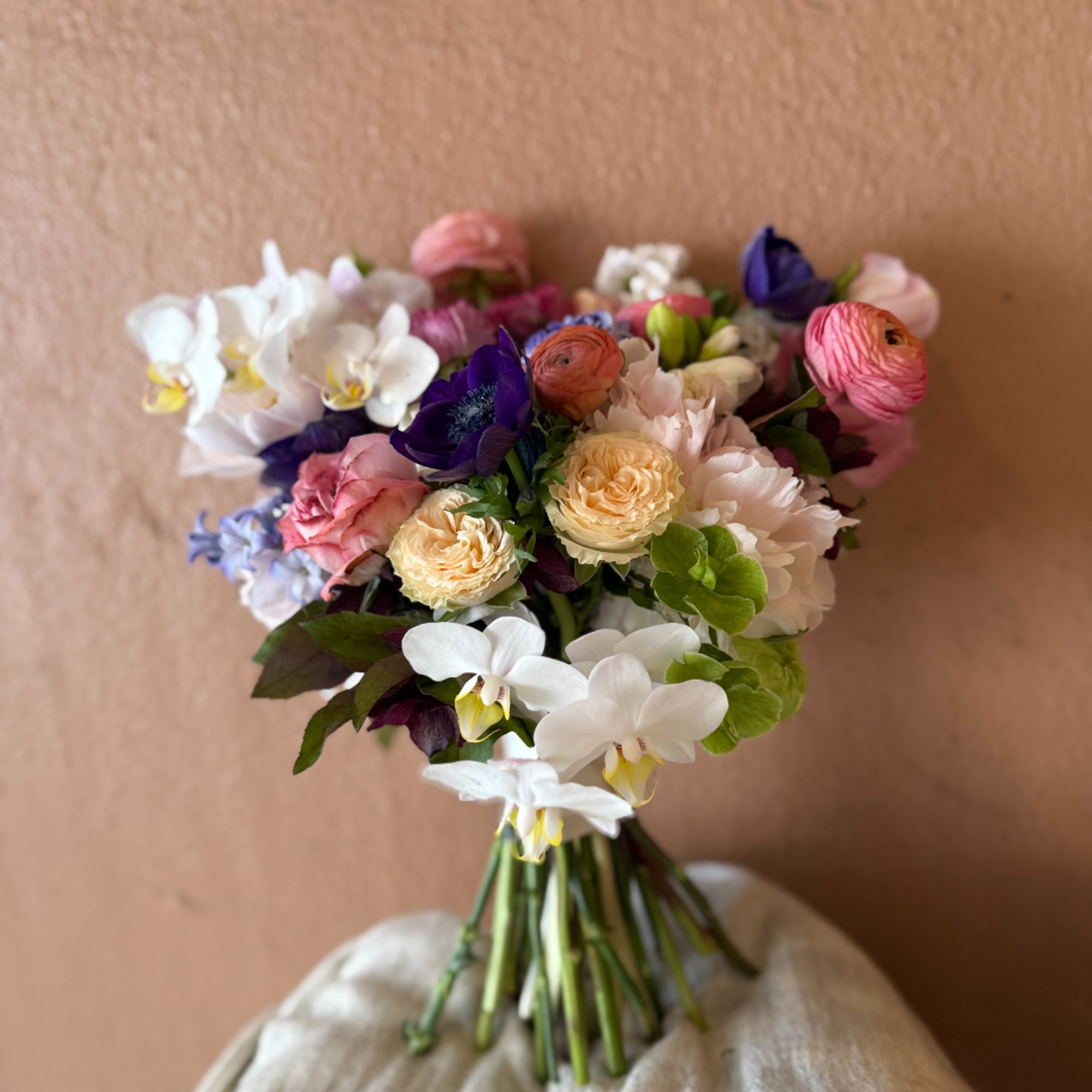 Wedding bouquet with white orchids, pink and cream roses, and purple blooms