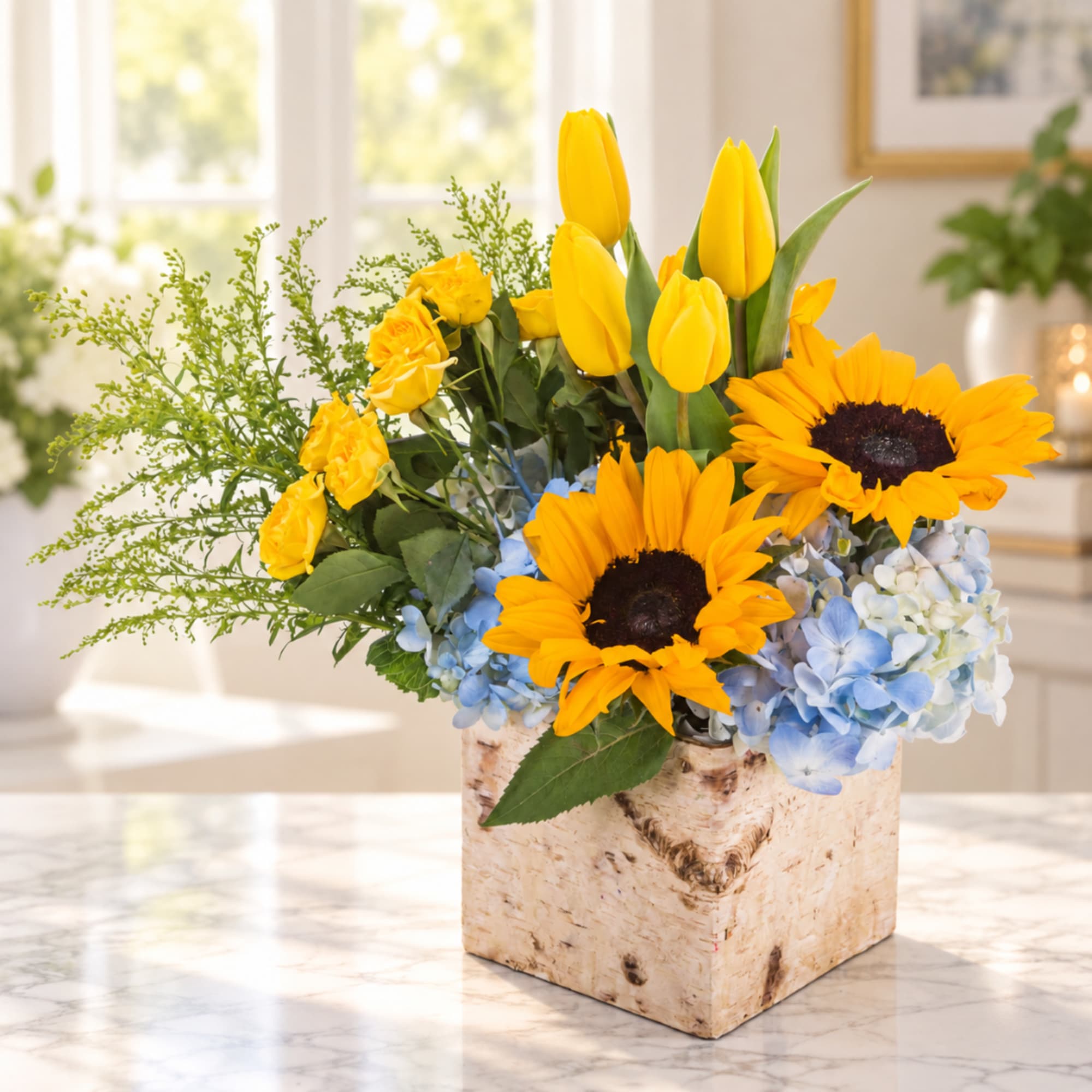 Sunflowers, yellow tulips, roses, and blue hydrangeas in a birch box