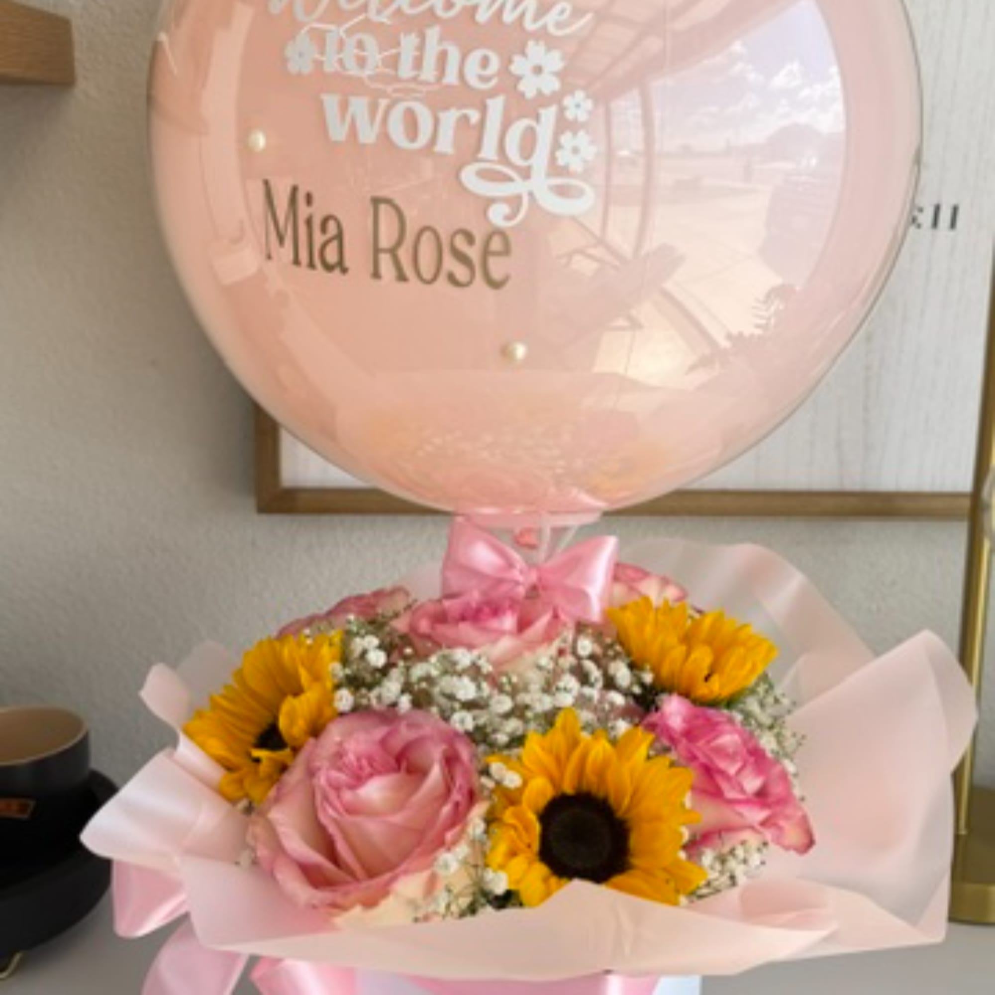 Pink bouquet with sunflowers and roses topped by a clear balloon