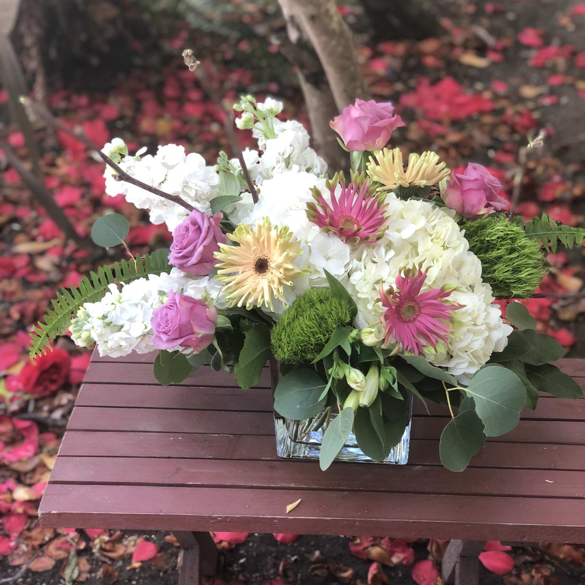 Mixed bouquet with pink roses, white blooms, and gerbera daisies in a glass vase