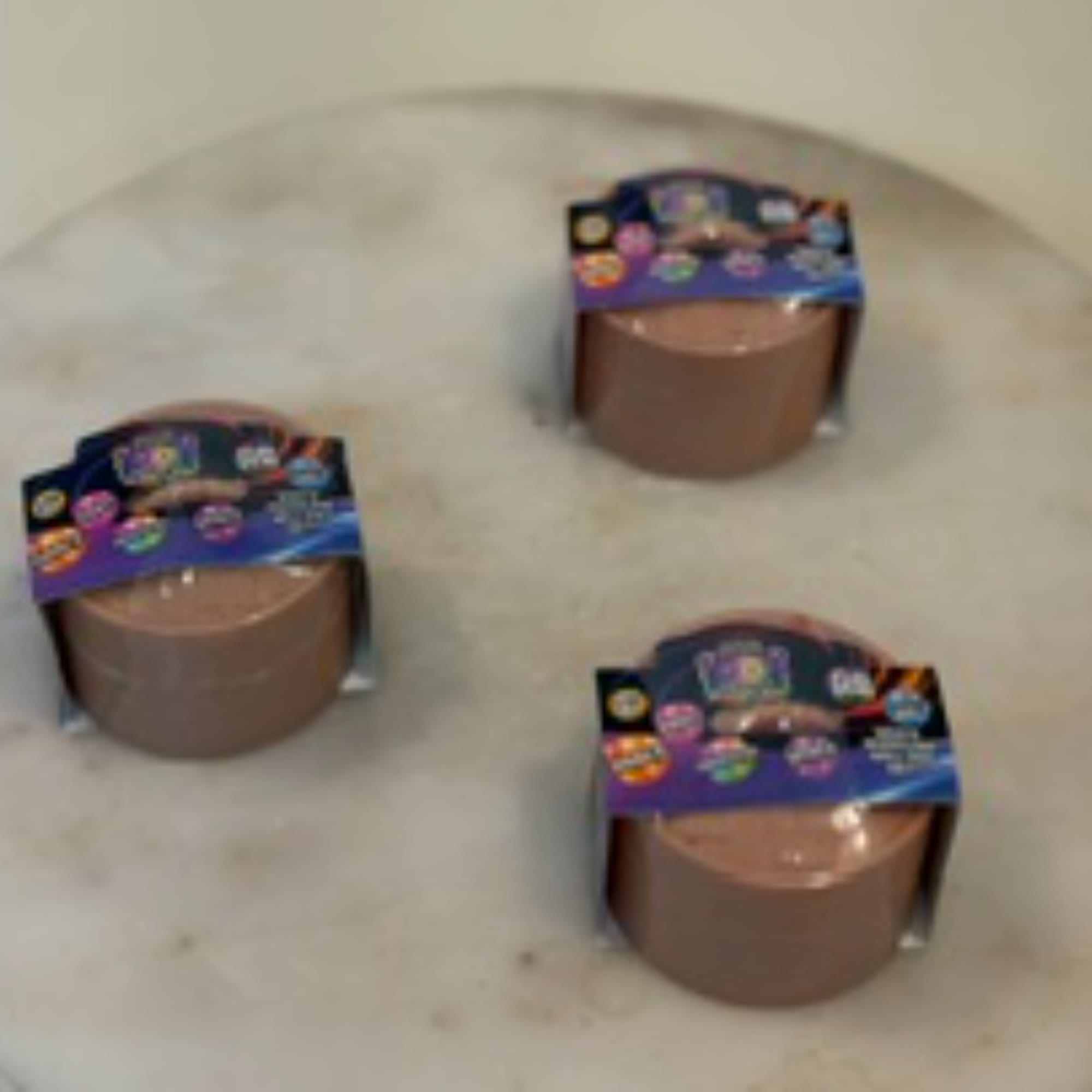 Three small candles in round containers with colorful labels