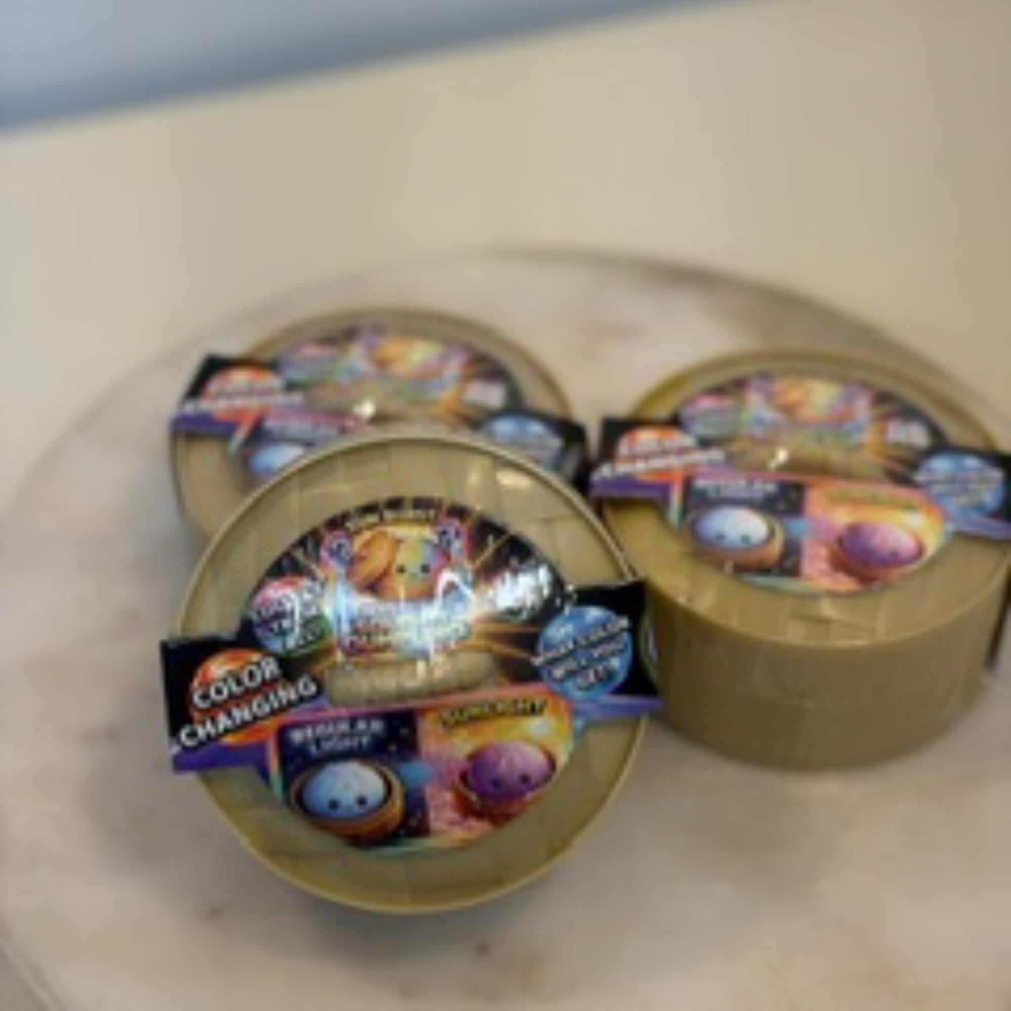 Three round tins of colorful candy or treats on a tray
