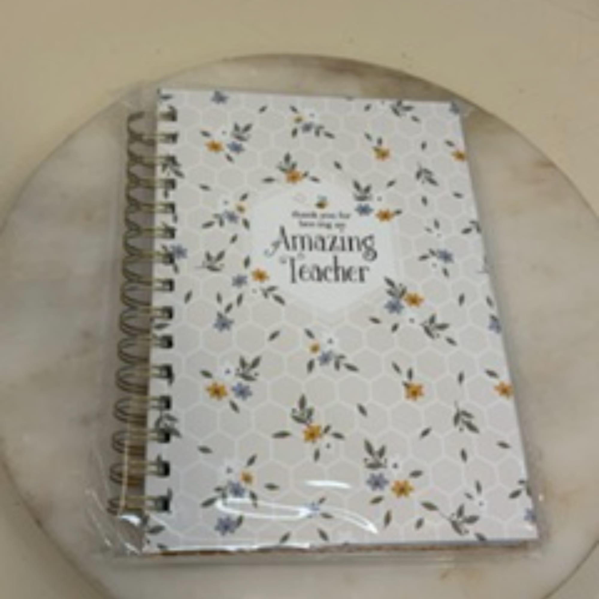 Spiral-bound notebook with a floral cover reading "Amazing Teacher"