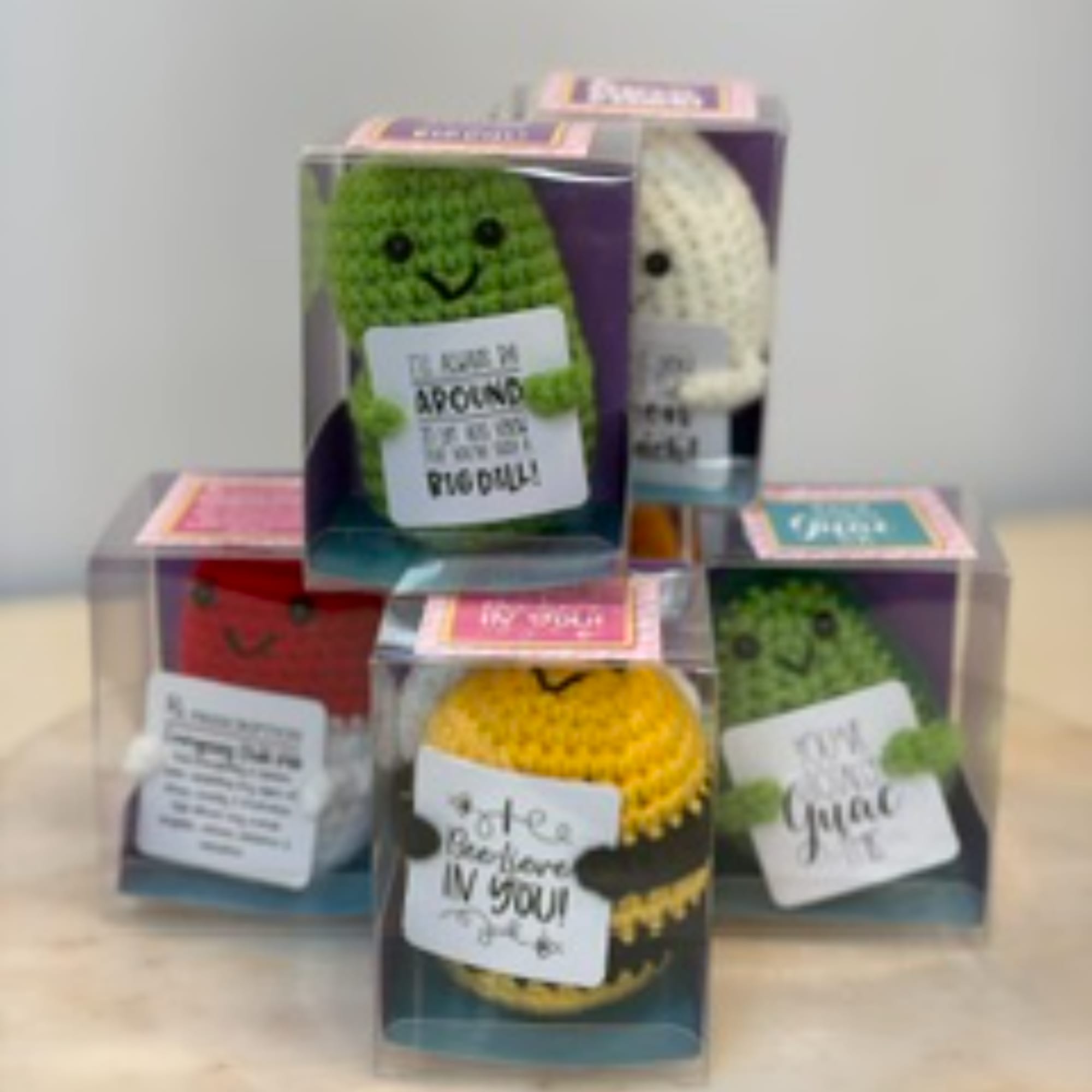 Boxed crocheted plush figures with handwritten message tags