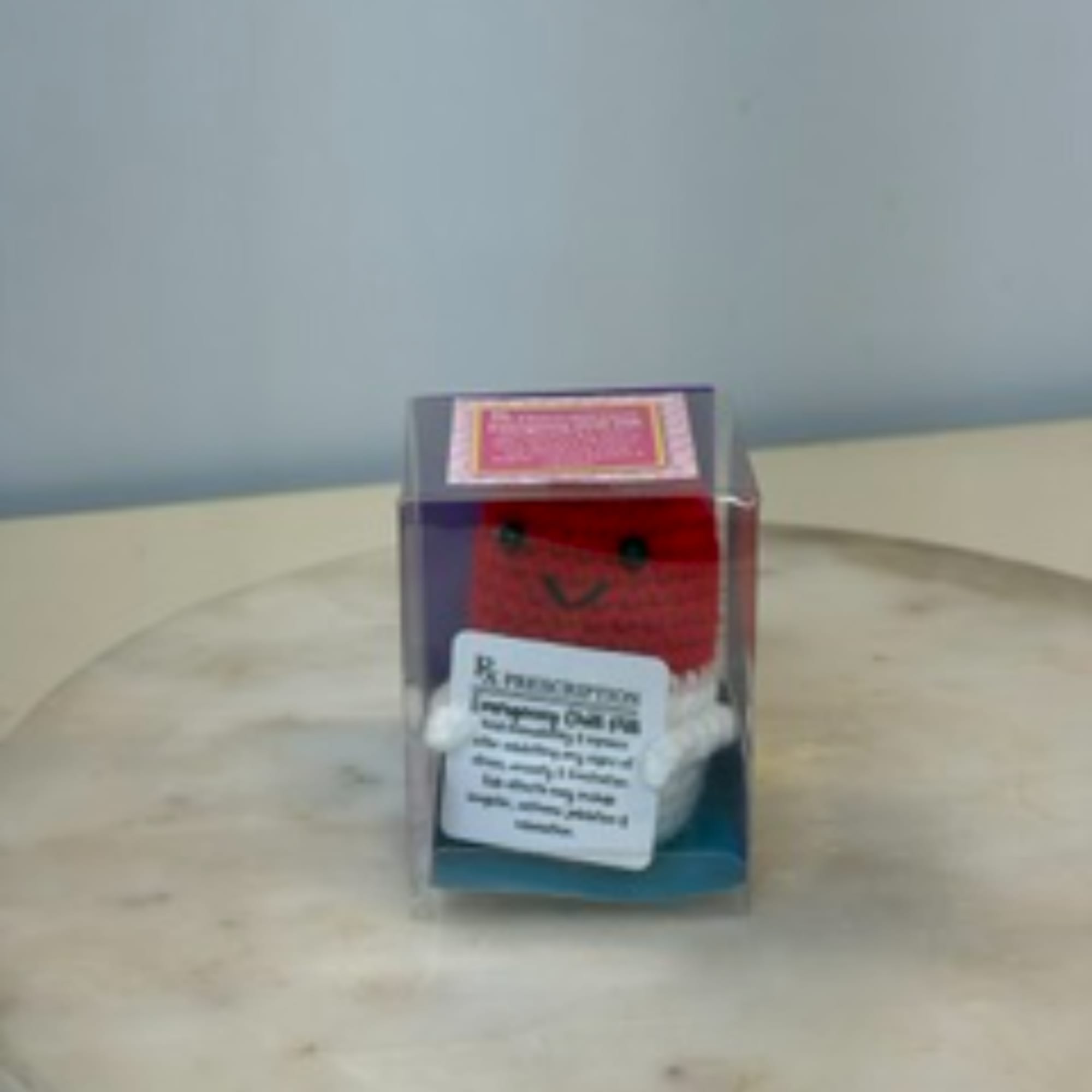 Small plush toy in a clear display box on a table