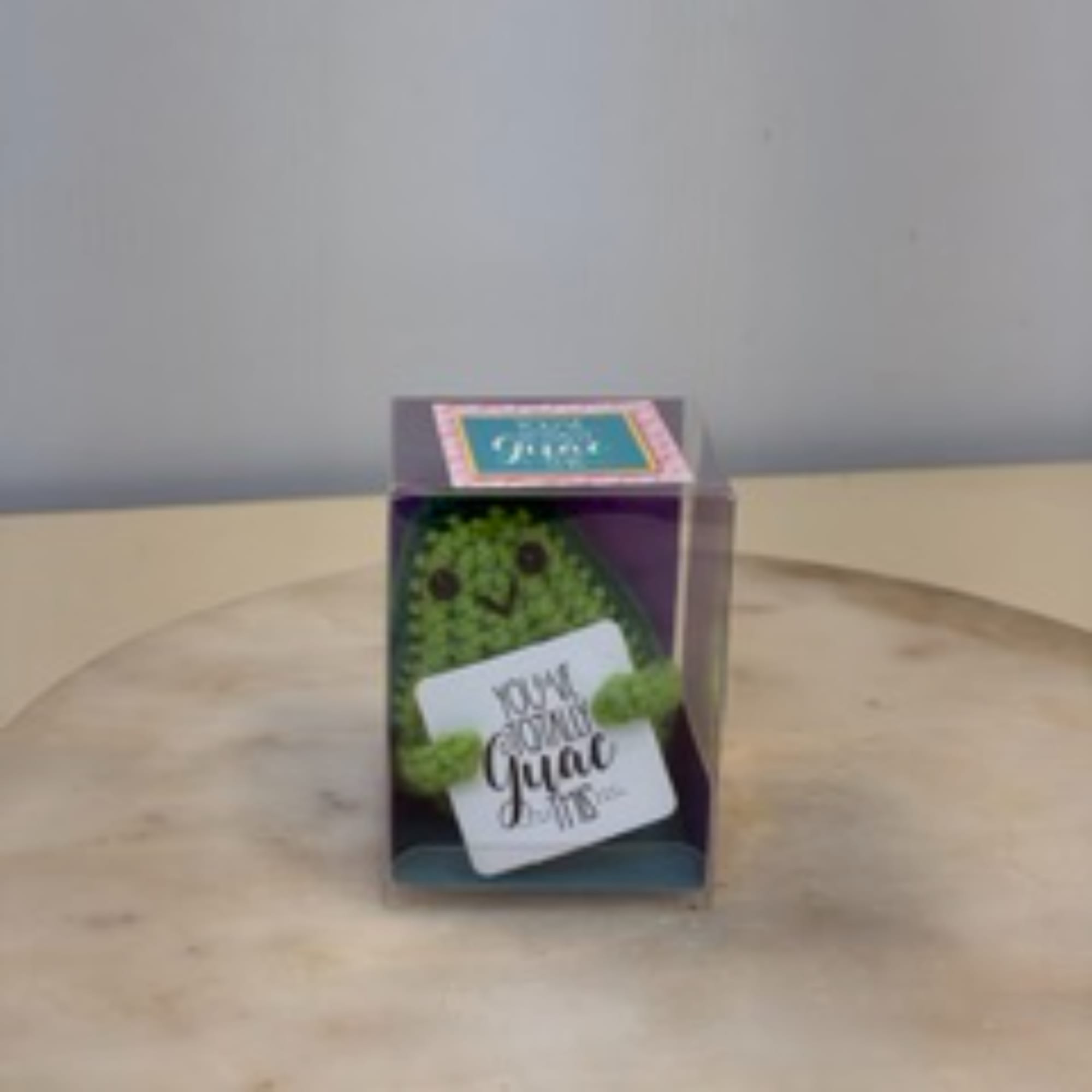Small boxed green plush with a face and a gift tag
