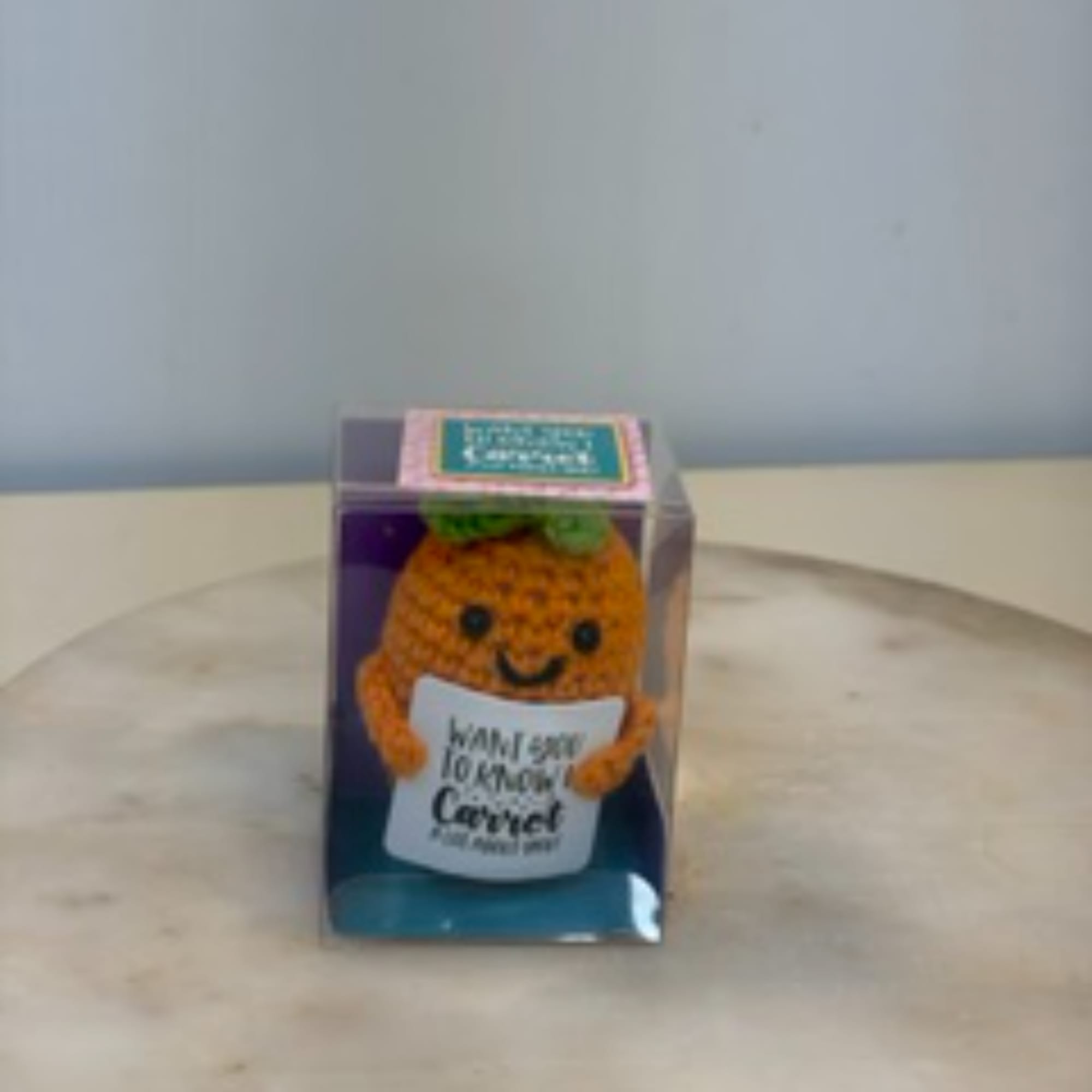 Small boxed plush carrot character holding a sign