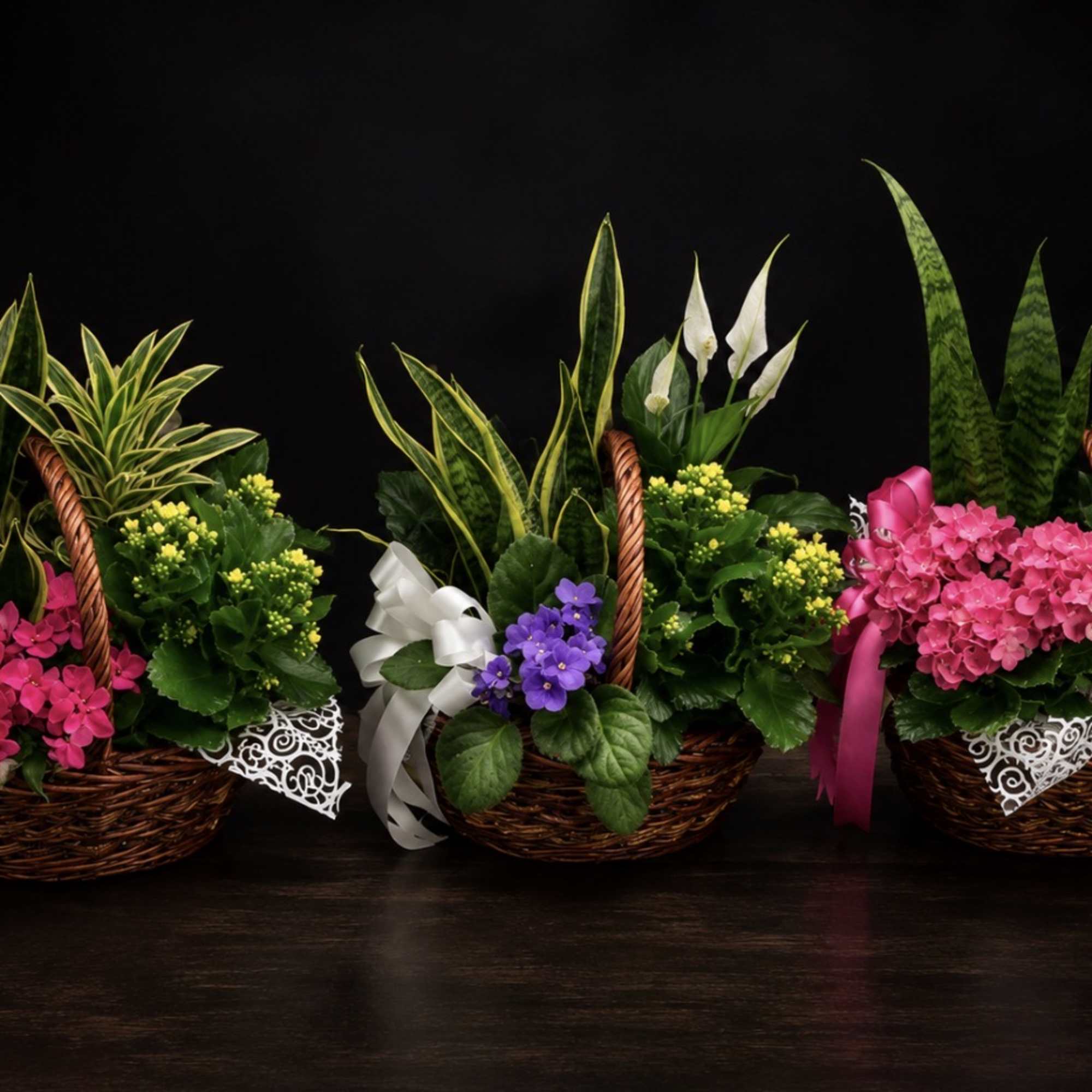 Three basket arrangements with mixed flowers and ribbon bows