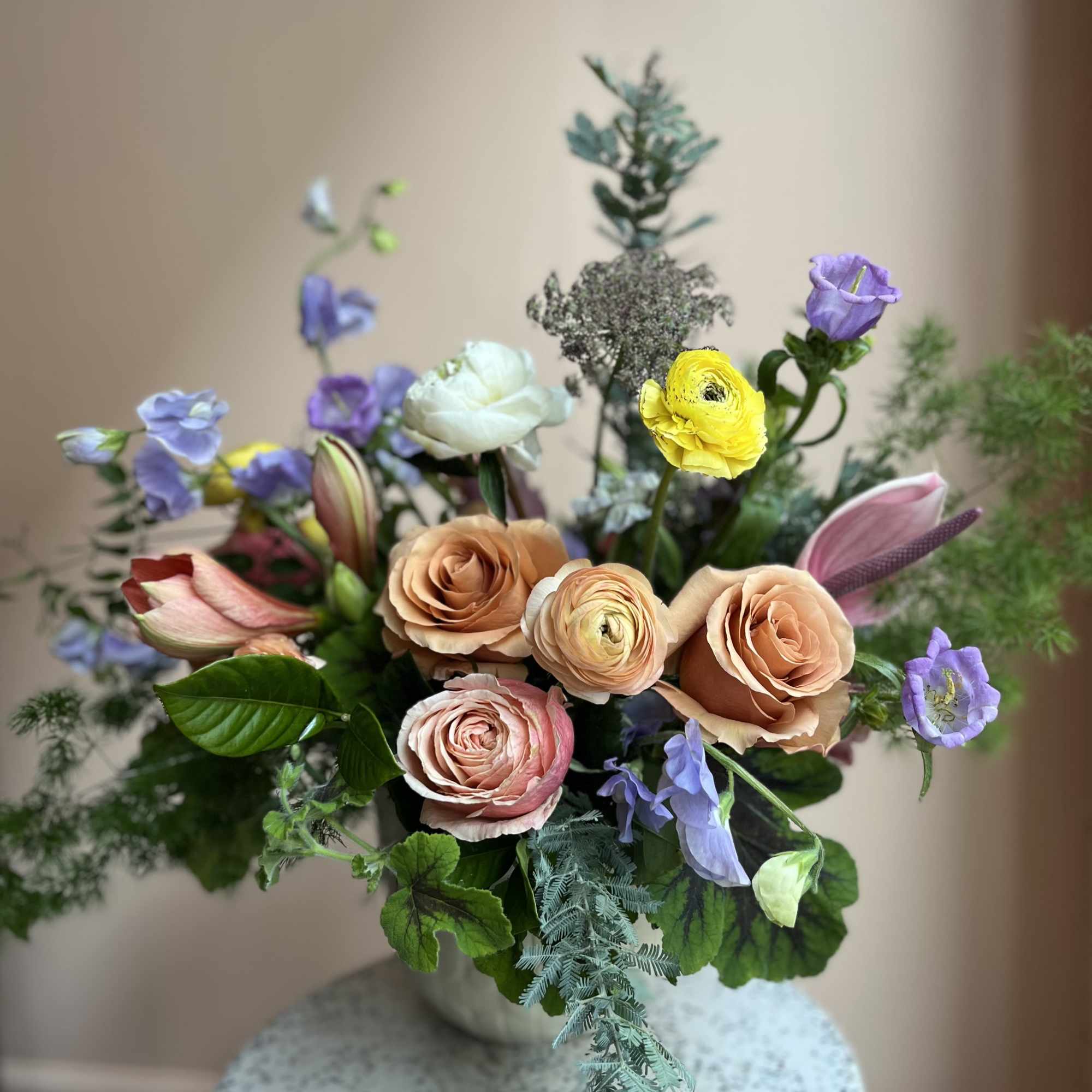 Mixed bouquet of peach roses and purple blooms in a vase