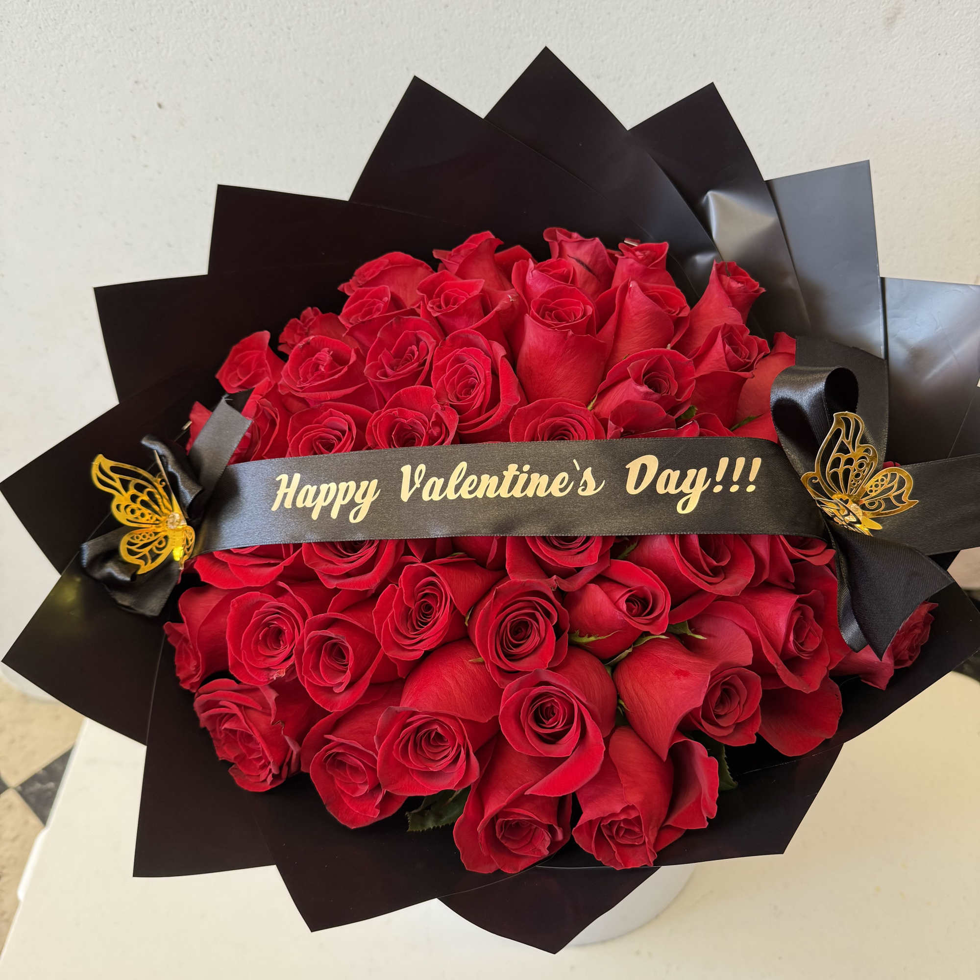 Bouquet of red roses wrapped in black paper with a Valentine’s Day ribbon
