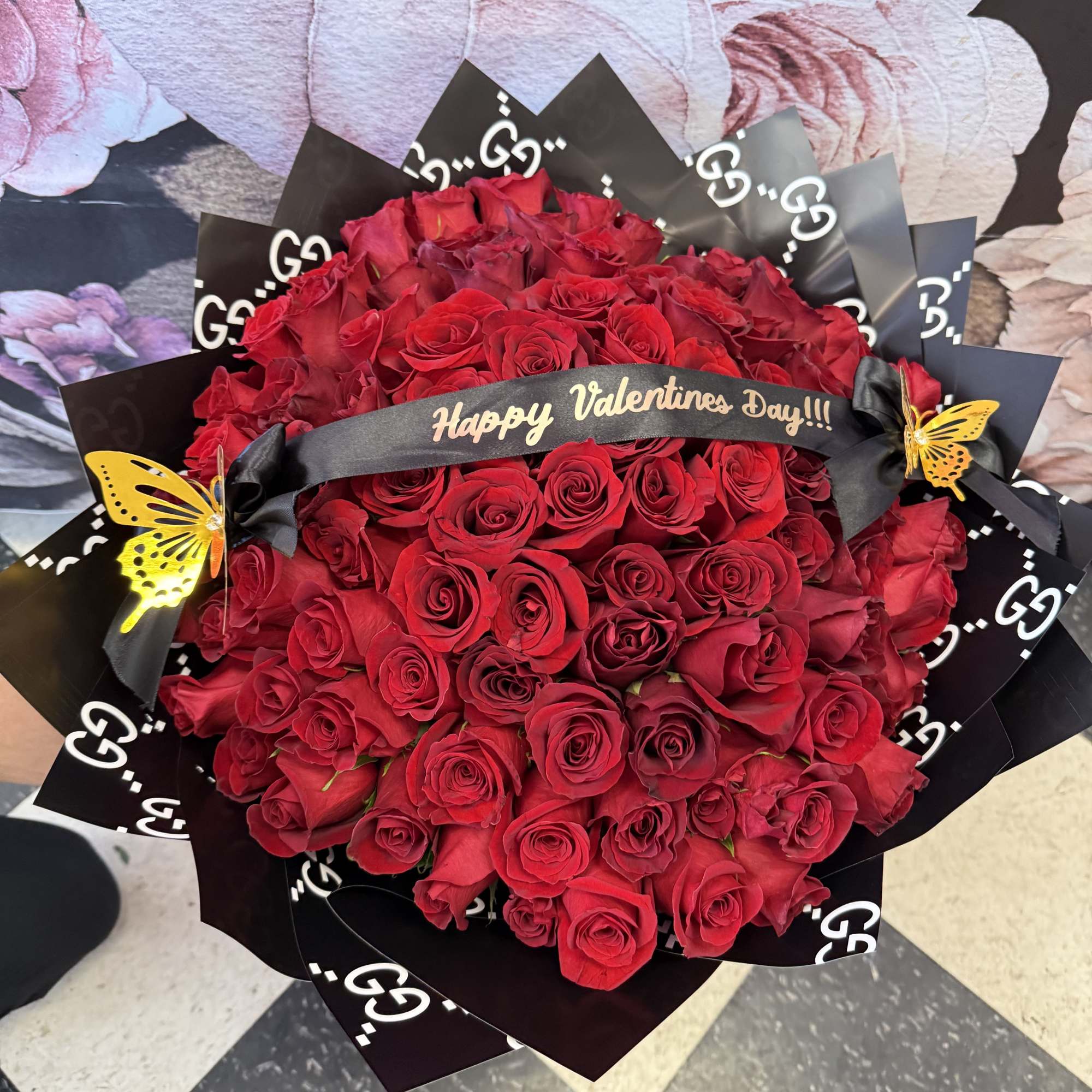 Large bouquet of red roses wrapped in black paper with a Valentine ribbon