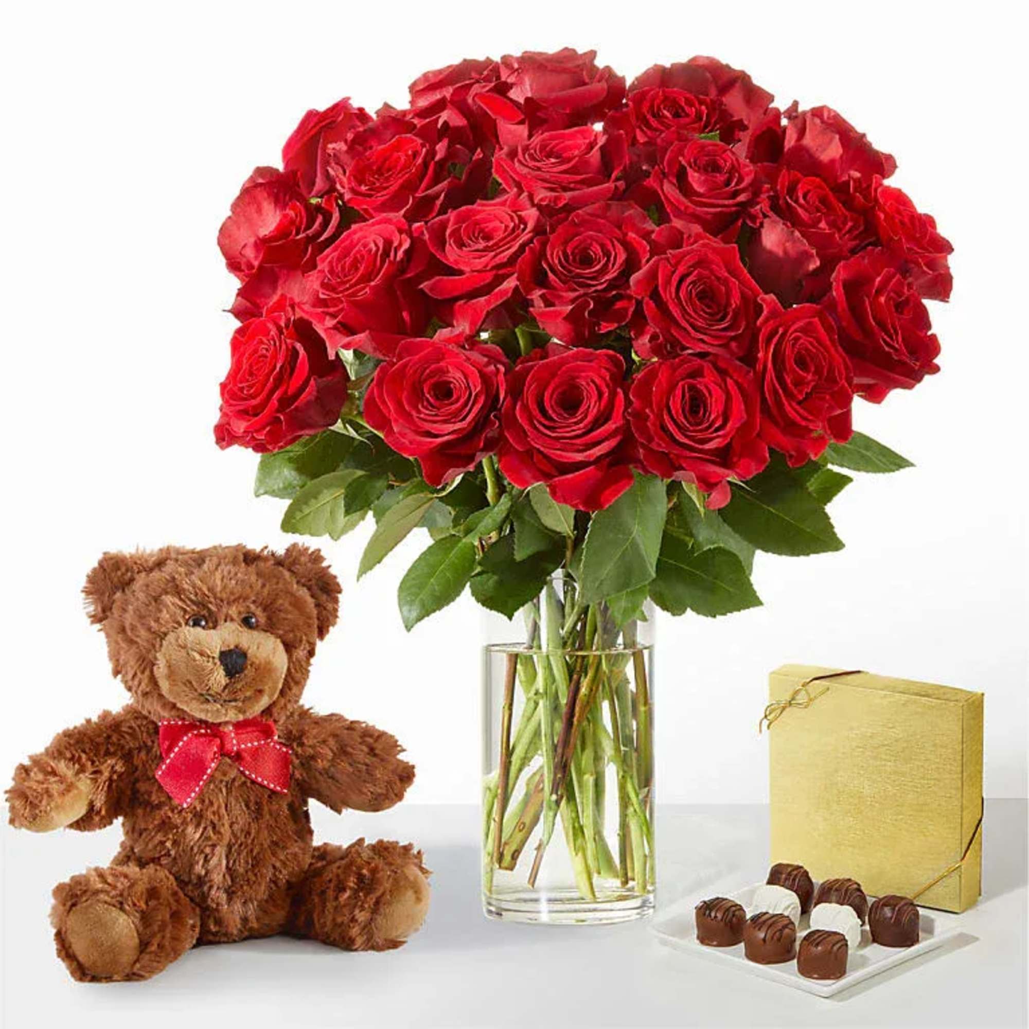 Red roses in a glass vase with a teddy bear and chocolates