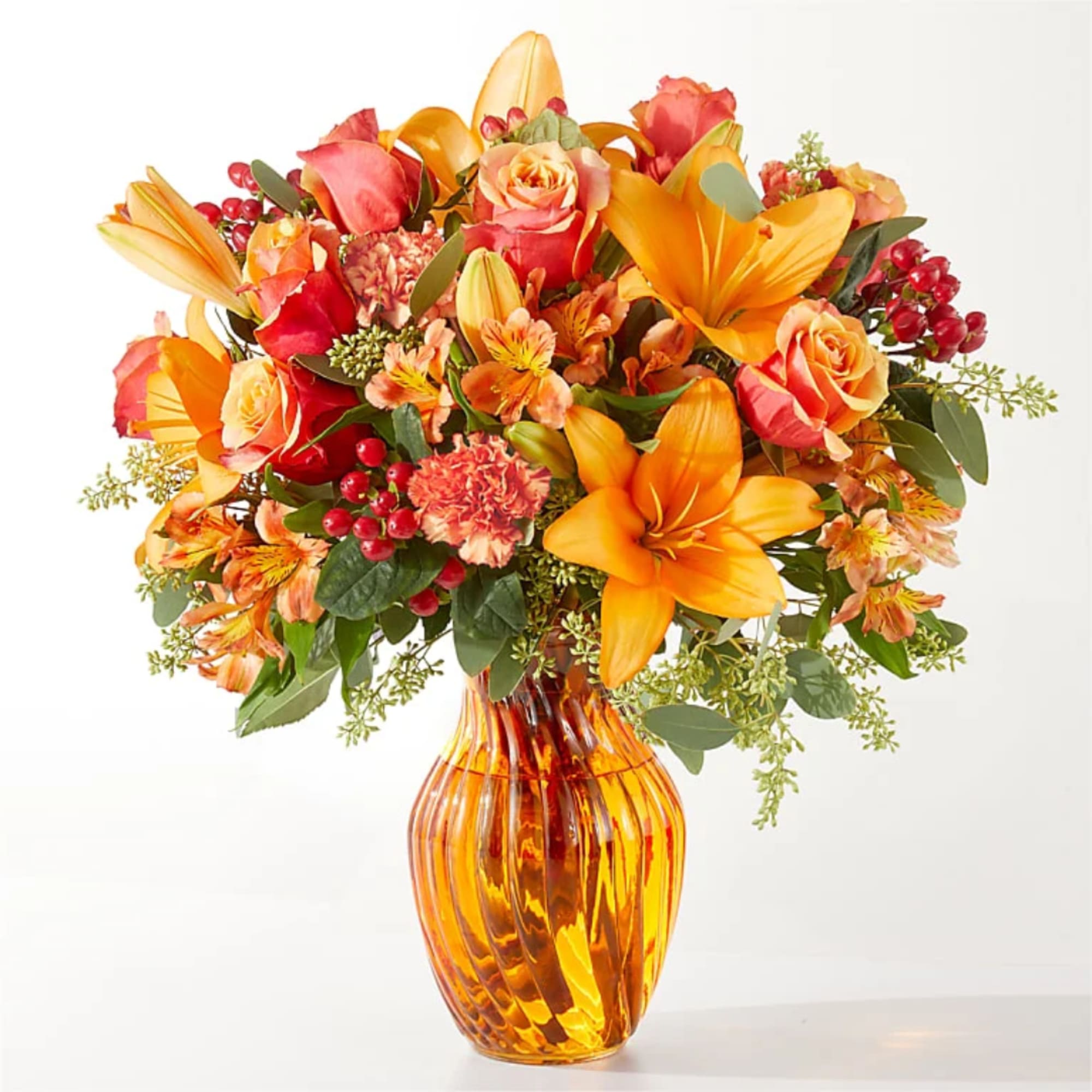 Orange and pink mixed bouquet in an amber glass vase