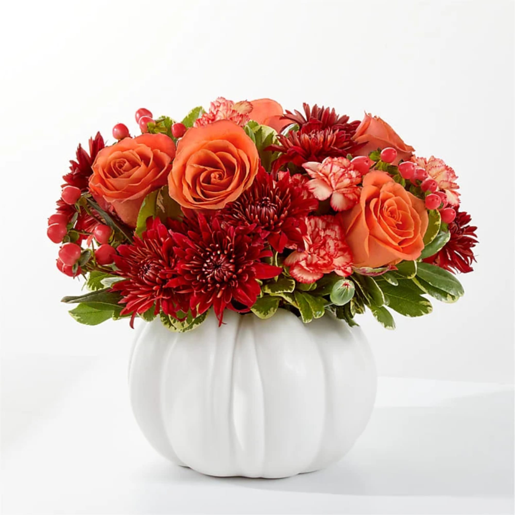 Orange roses and red mums in a white pumpkin vase