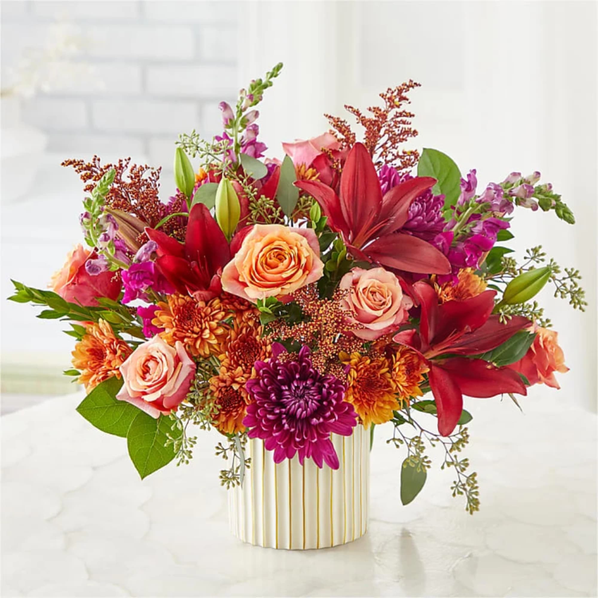 Mixed bouquet of roses, lilies, and mums in a striped vase