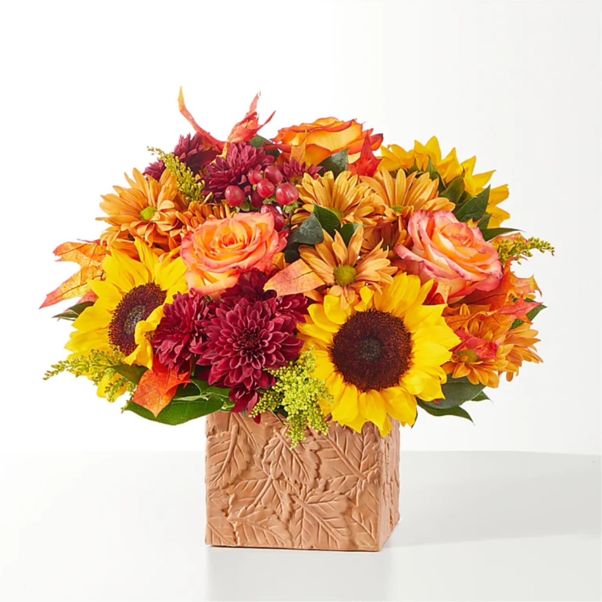 Autumn bouquet of sunflowers, roses, and mums in a leaf-patterned vase