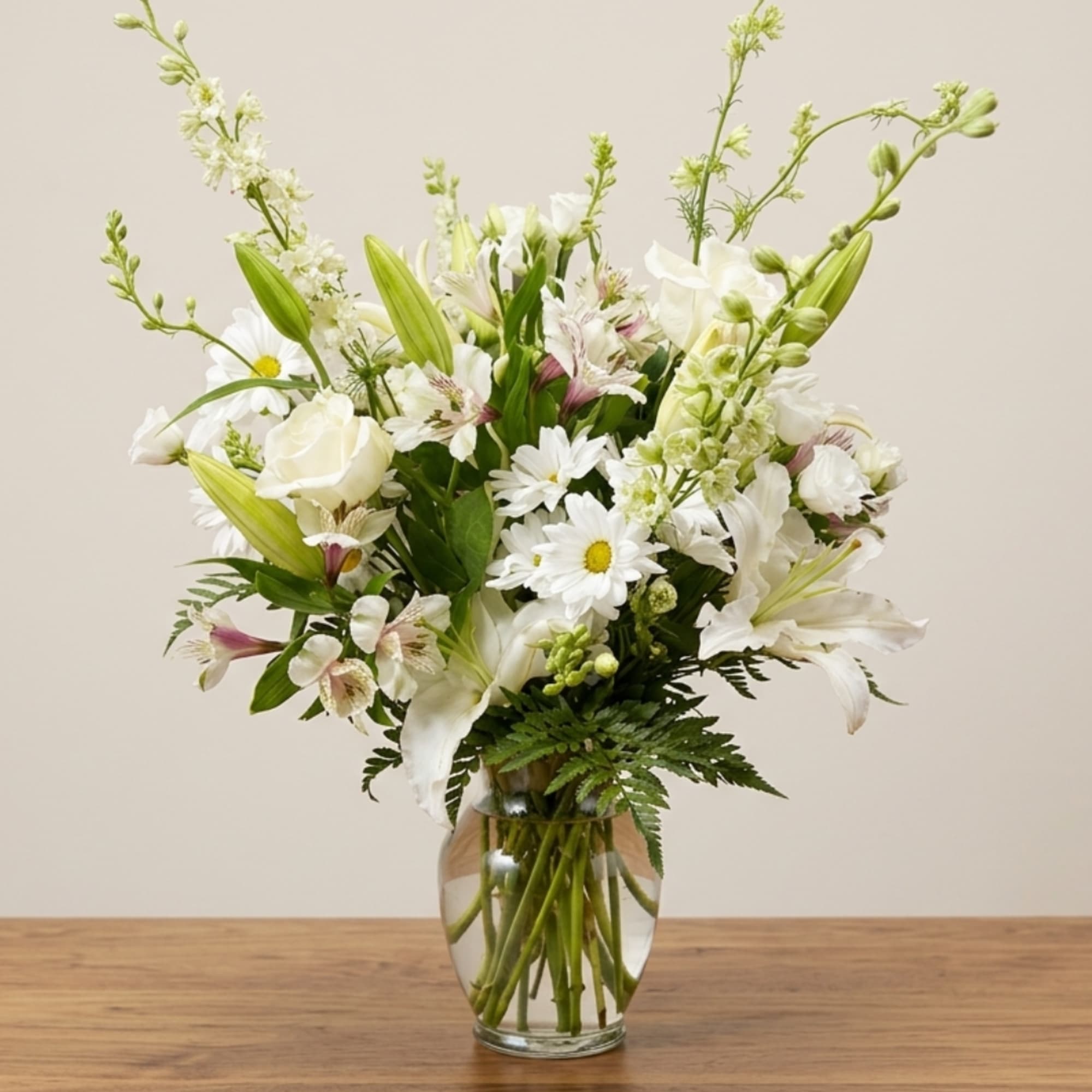 White flowers in a clear glass vase with green accents