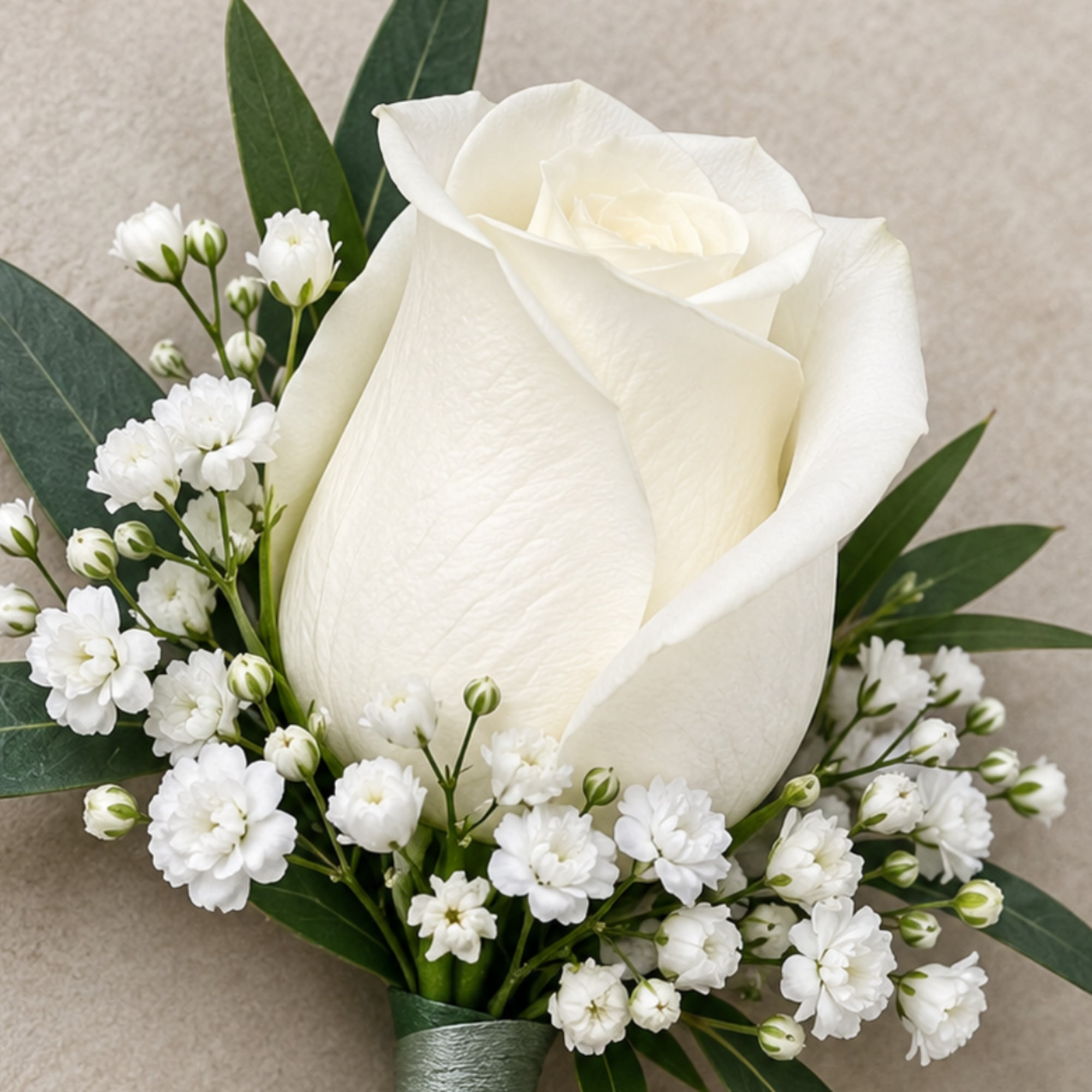White rose bouquet with small white filler flowers and dark green leaves