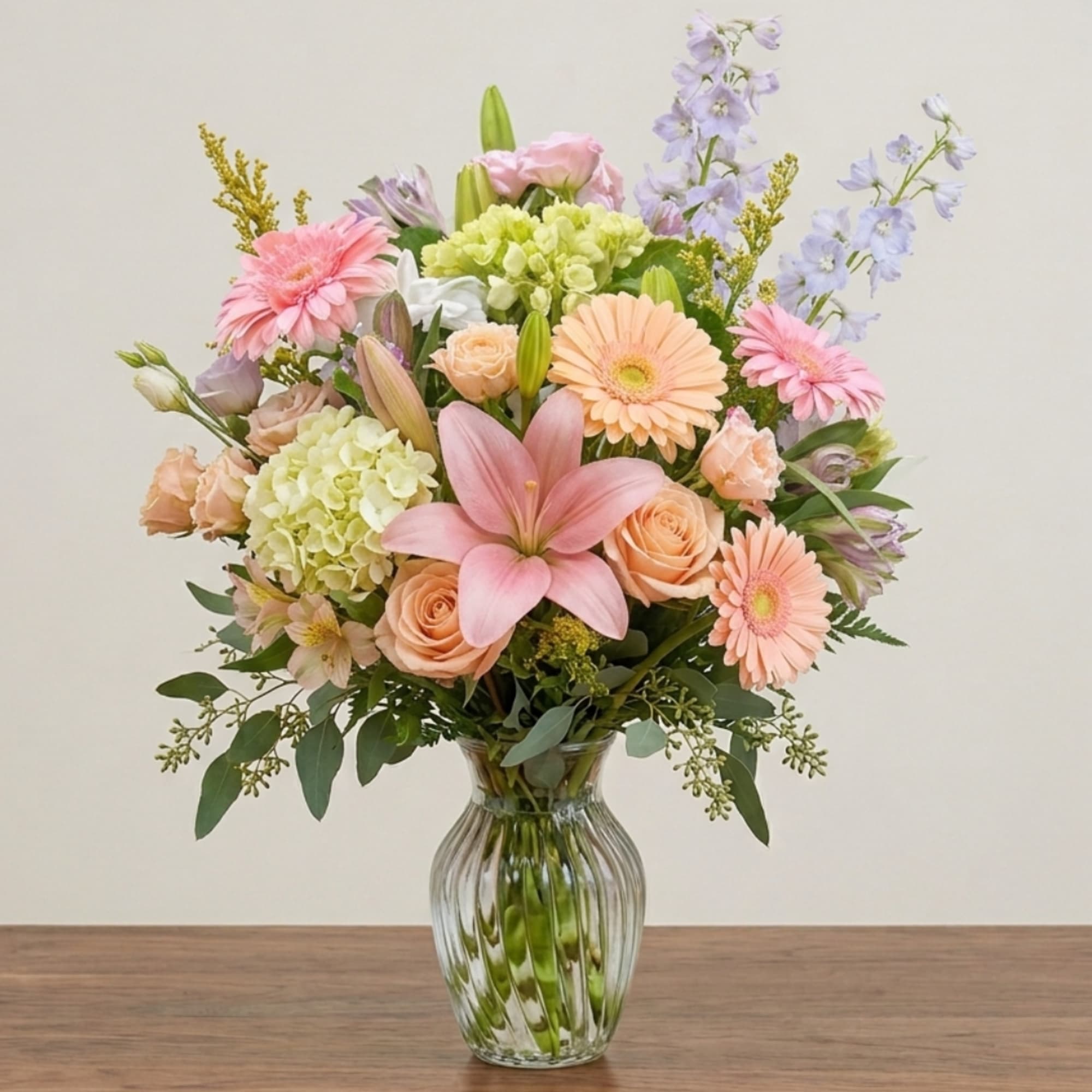 Pastel mixed bouquet in a clear glass vase with lilies and gerbera daisies