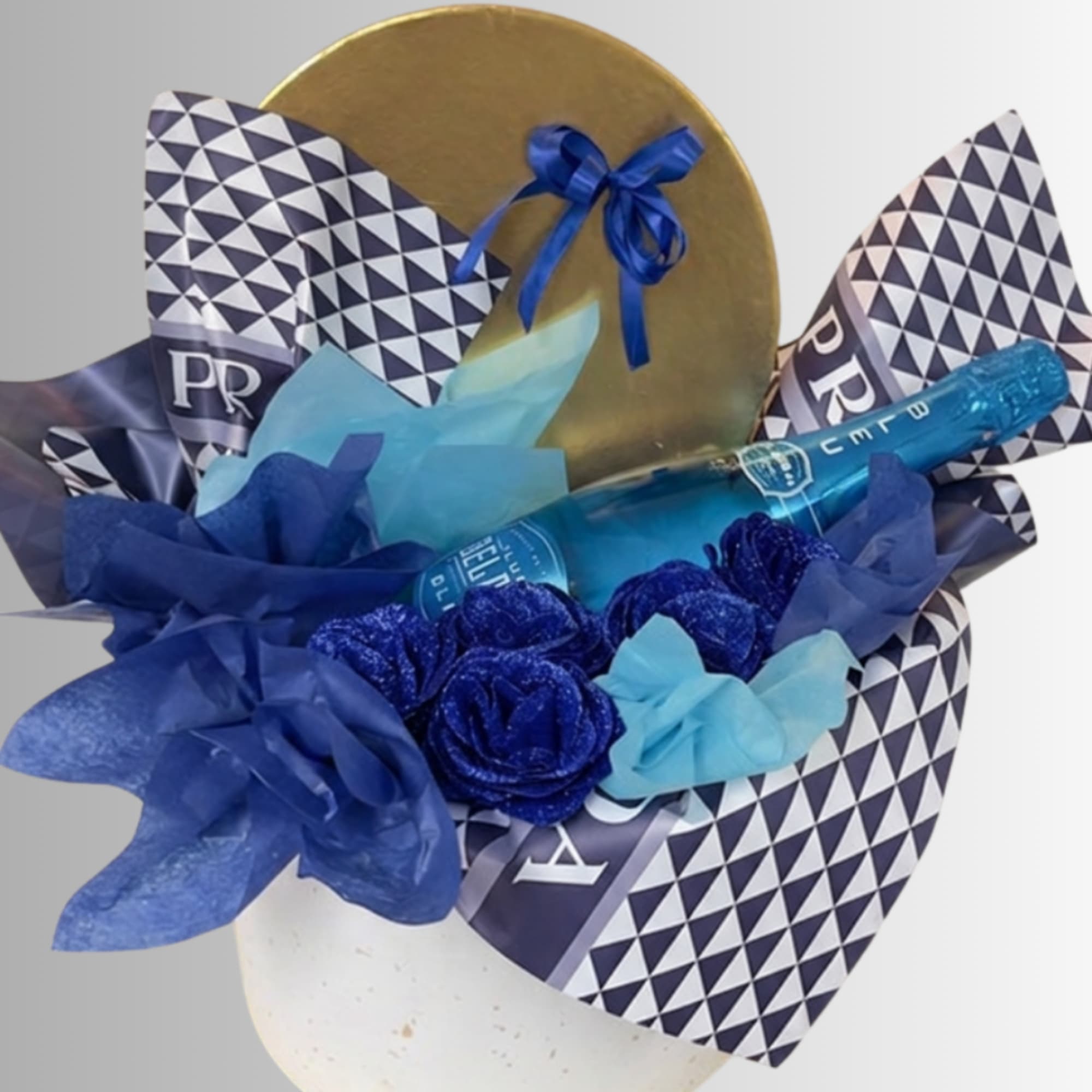 Blue gift arrangement with a champagne bottle and decorative paper flowers