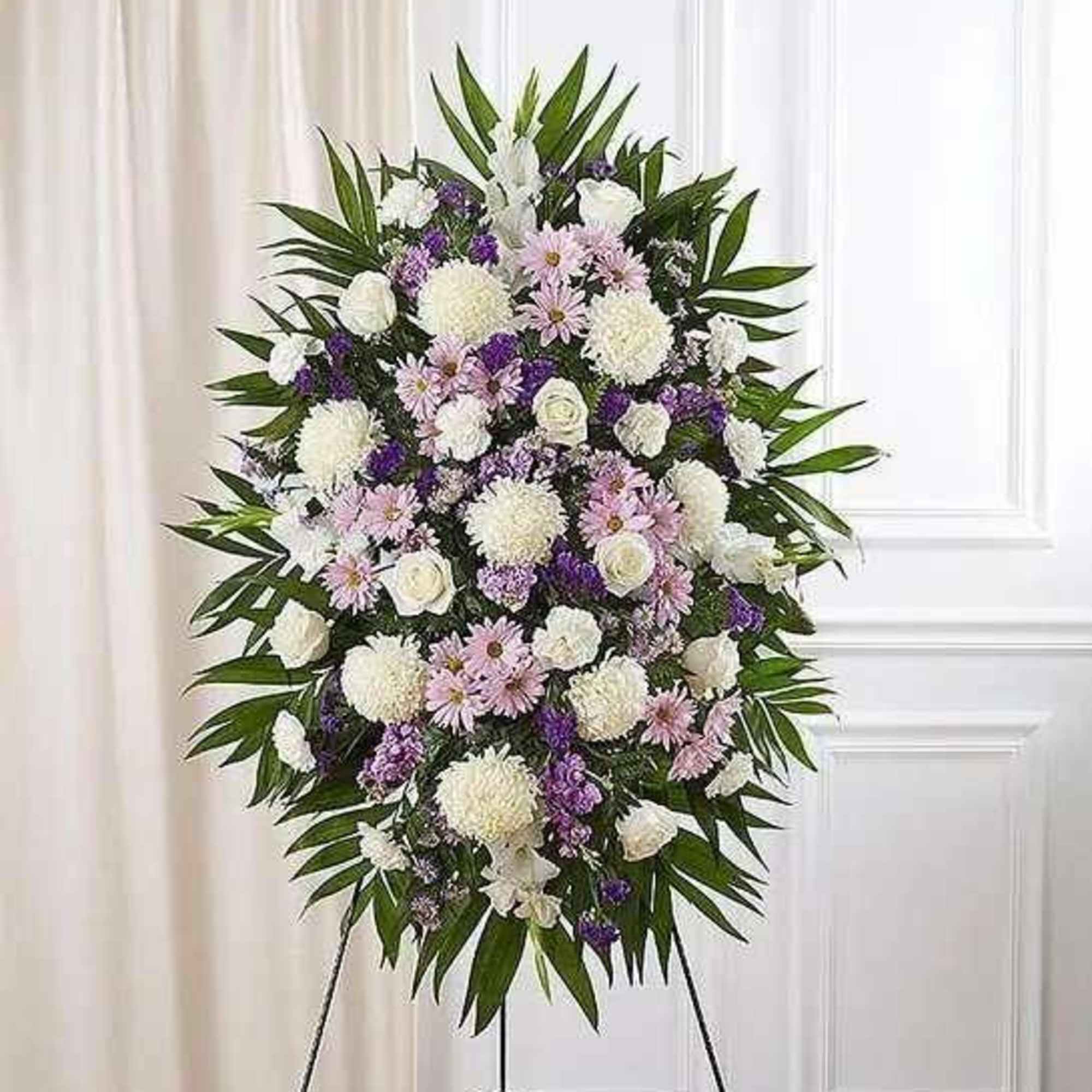 Standing funeral spray with white, pink, and purple flowers on an easel