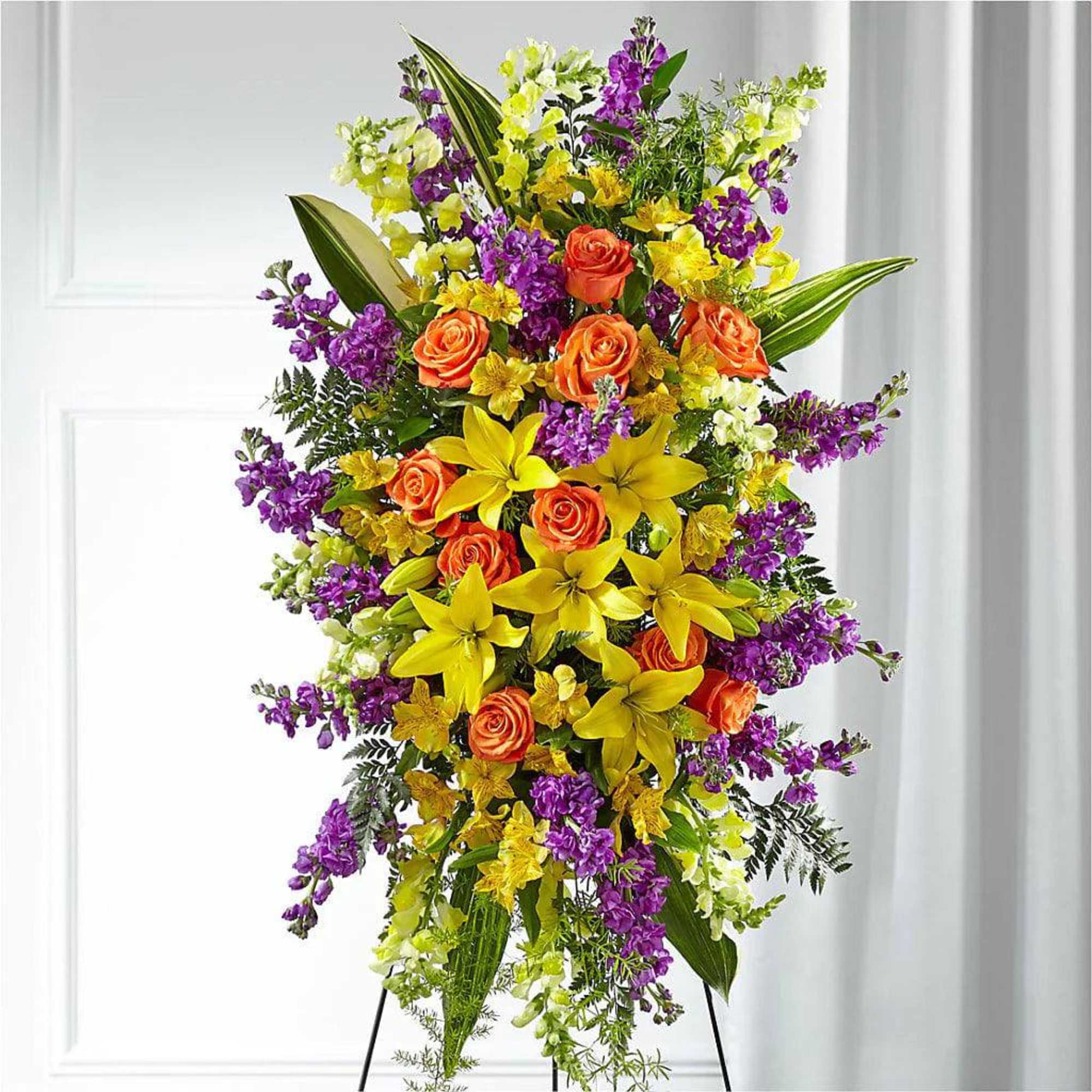 Tall standing floral spray with orange roses, yellow lilies, and purple blooms