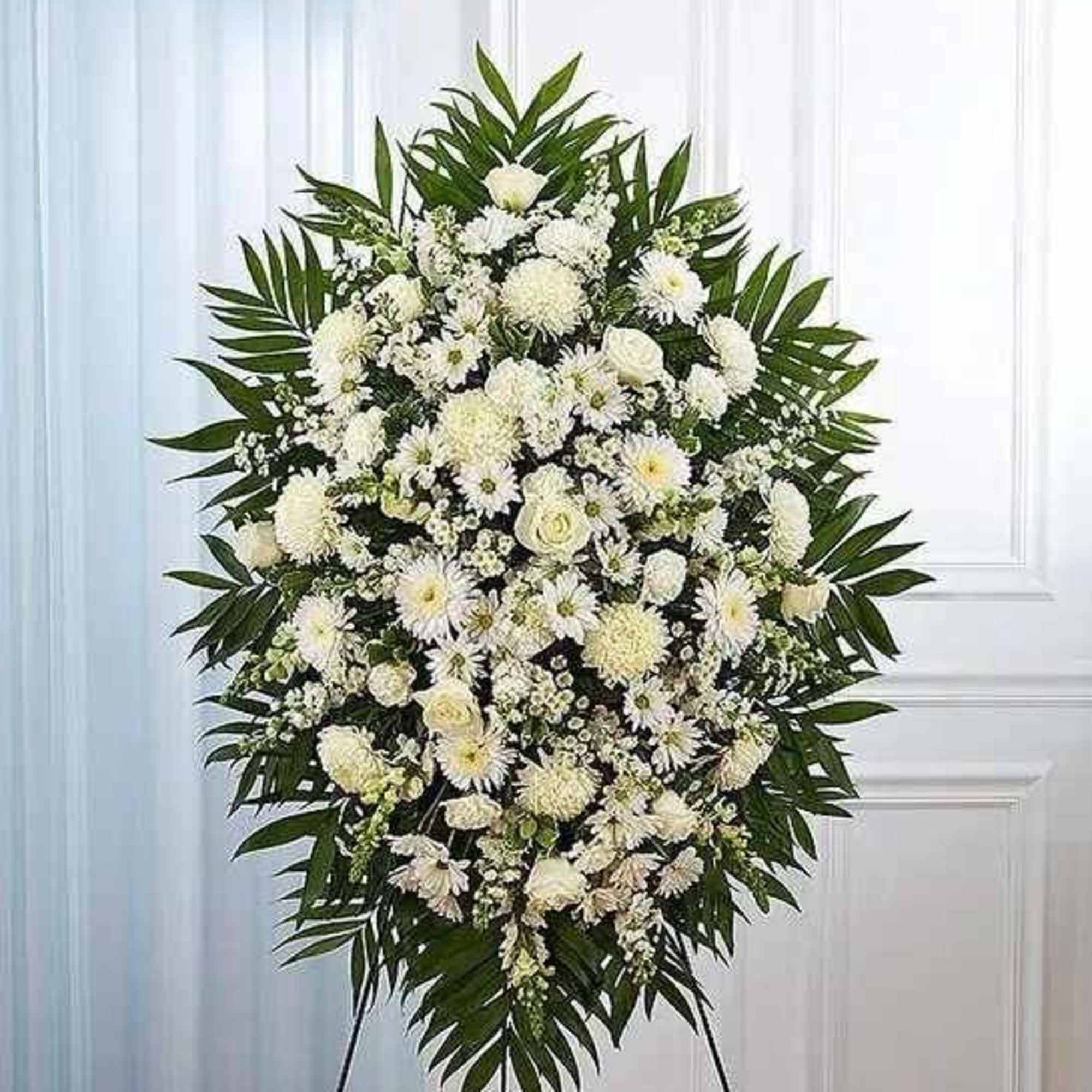 White funeral spray with mixed blooms on a standing easel
