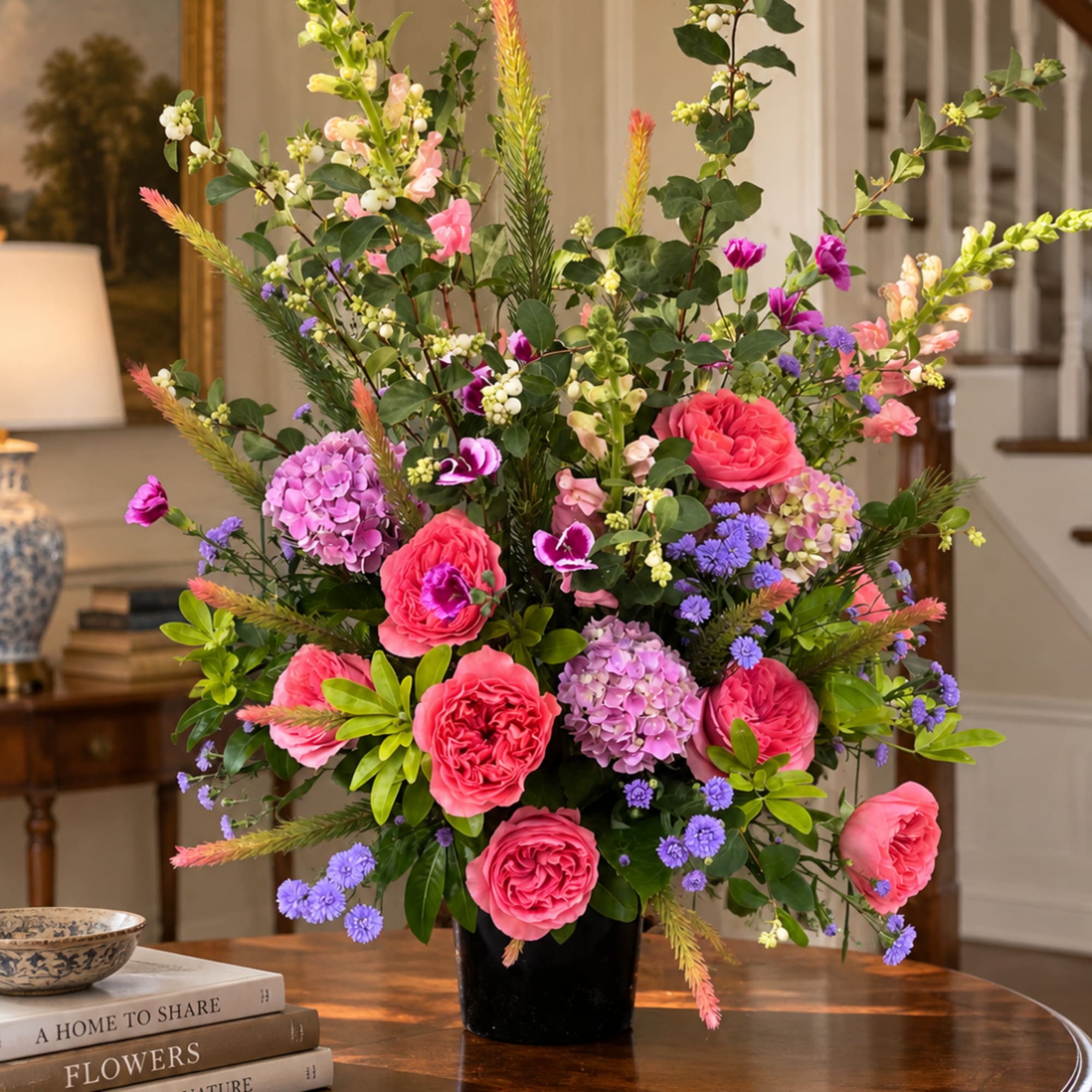 Pink and purple floral arrangement in a black vase on a table