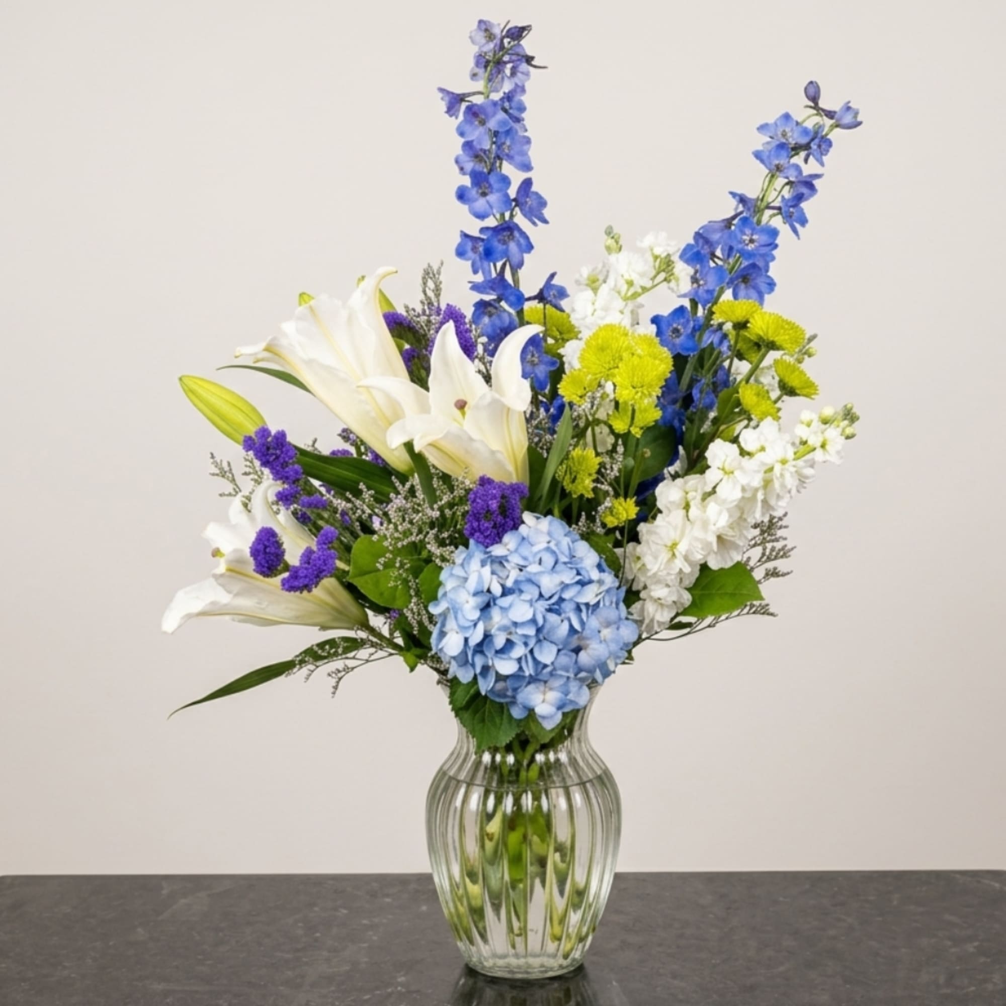 Blue and white mixed flower arrangement in a clear glass vase, photo 2 of 2