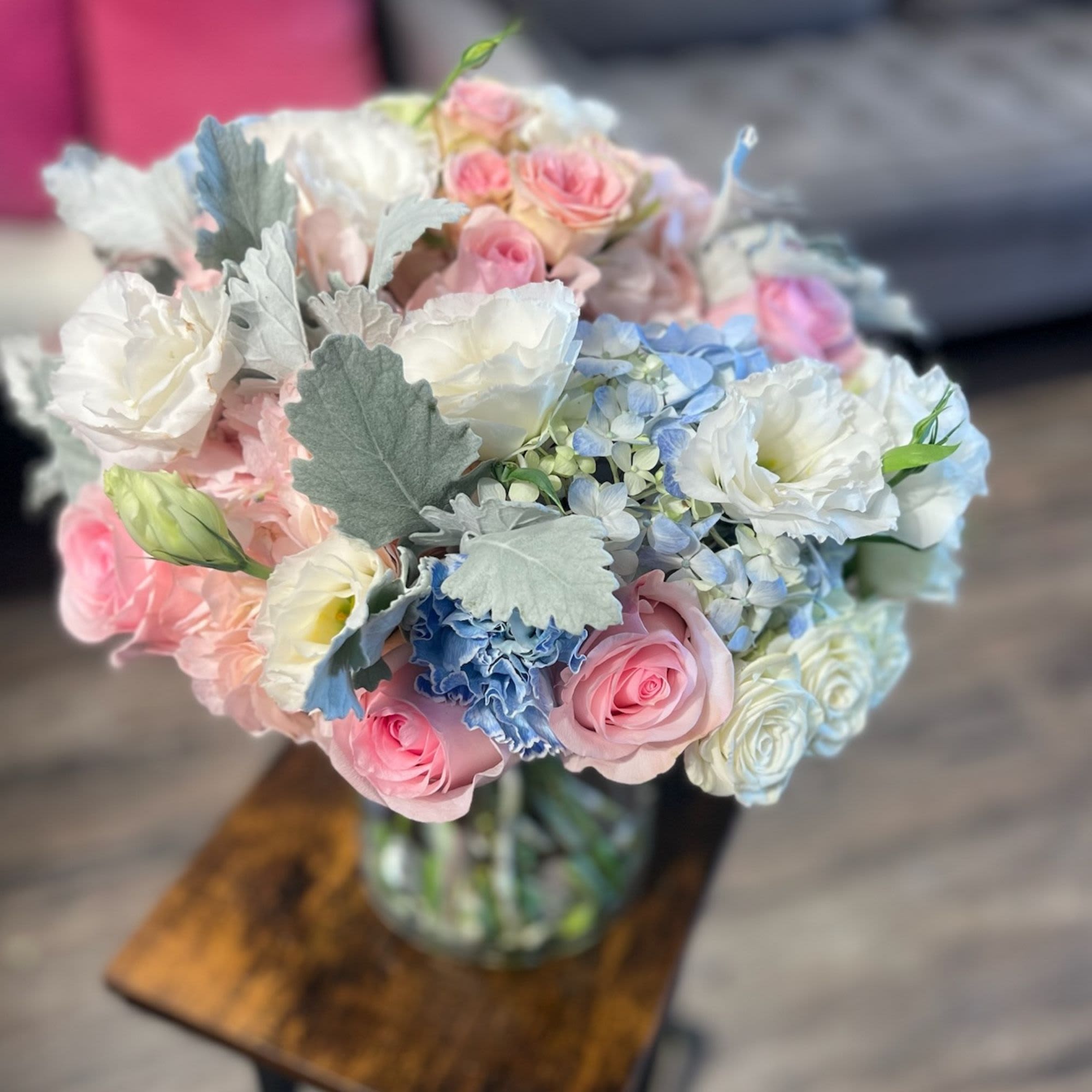 Bouquet of pink and white roses with blue hydrangeas in a glass vase