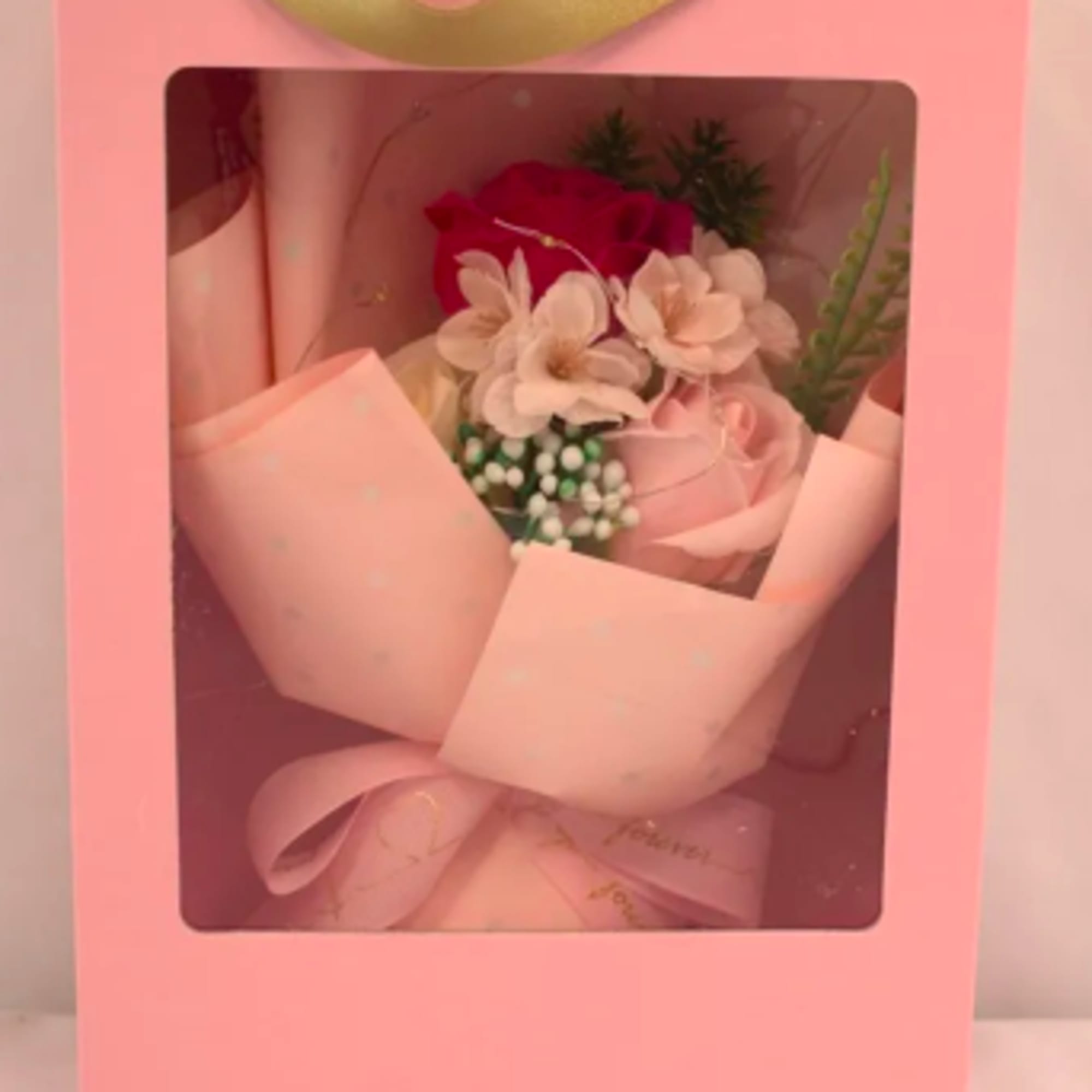 Small pink bouquet with roses and white blossoms in a pink window gift box with gold handle