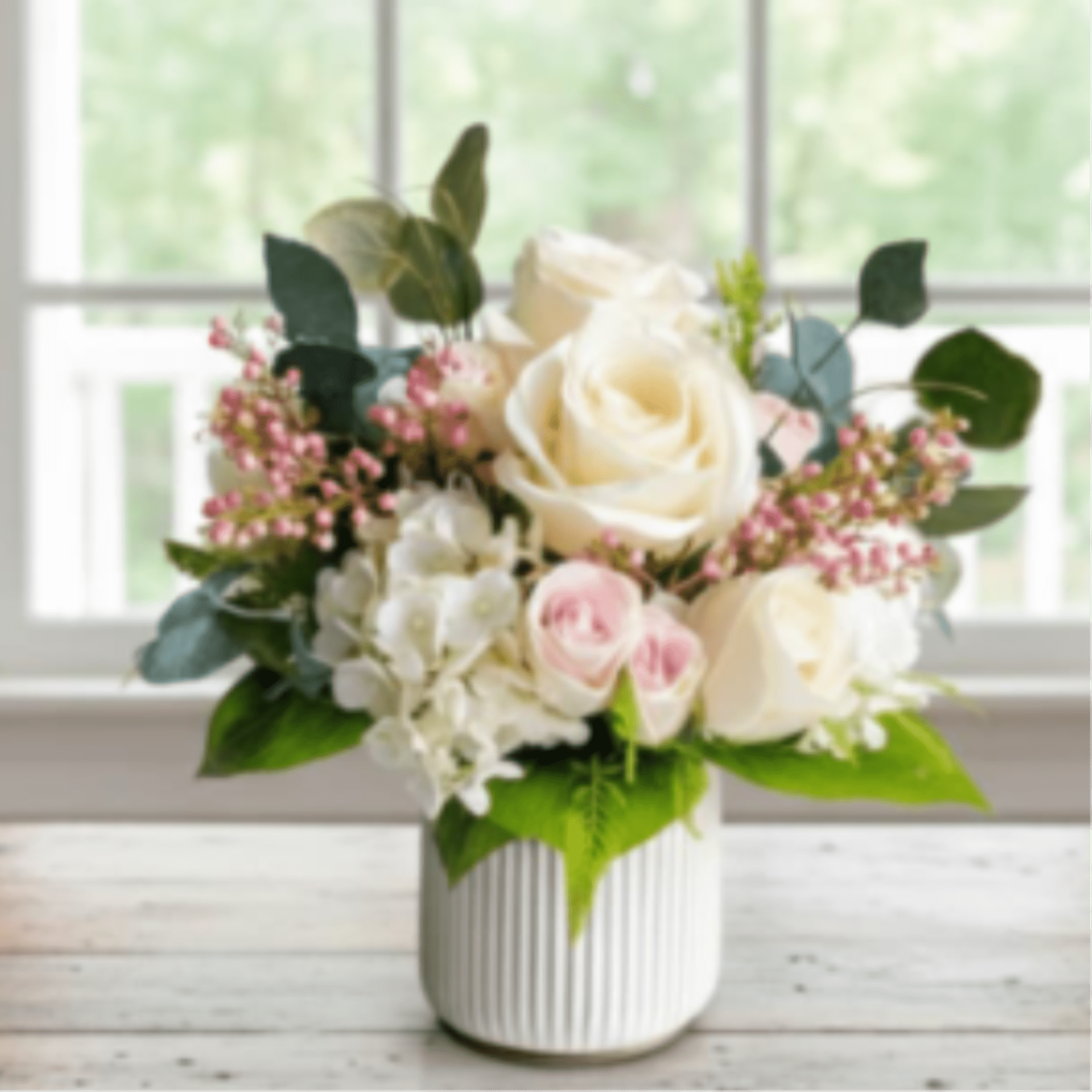 Cream roses and pink blooms in a white ribbed vase