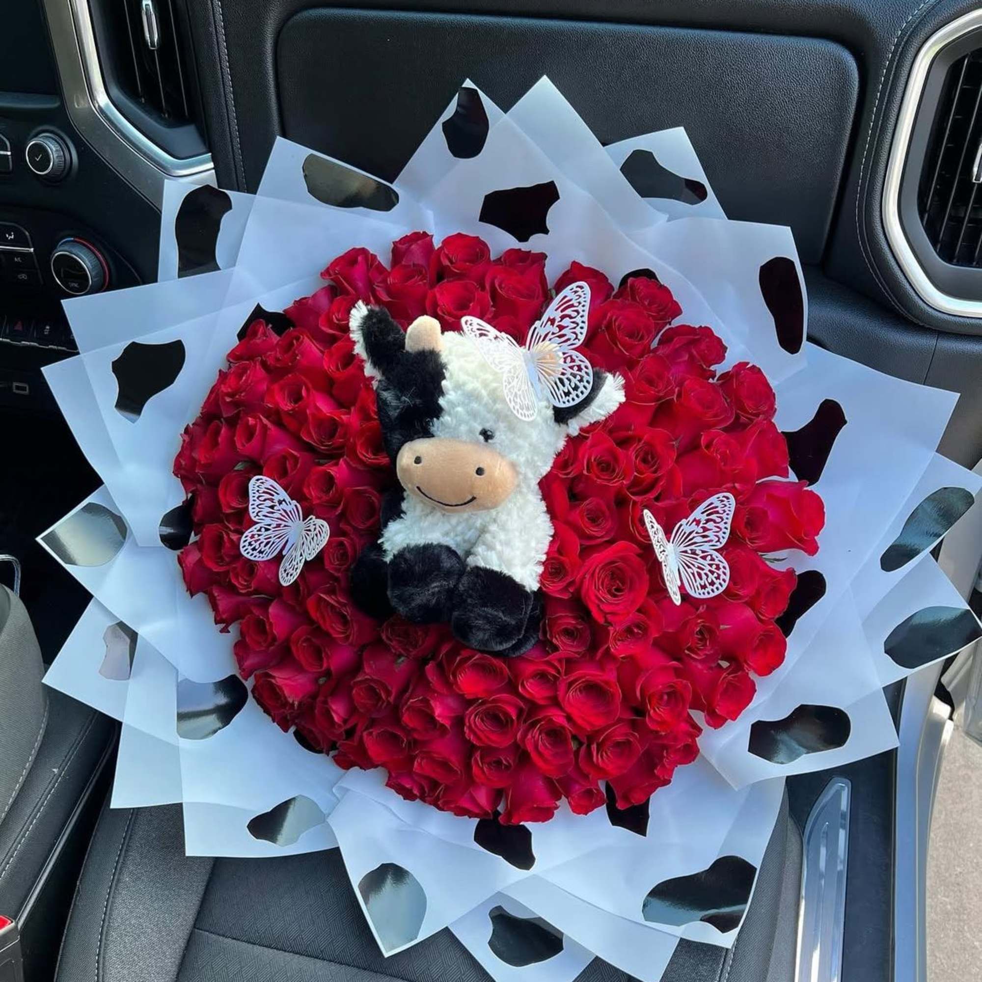 Bouquet of red roses with a plush cow and butterfly decorations