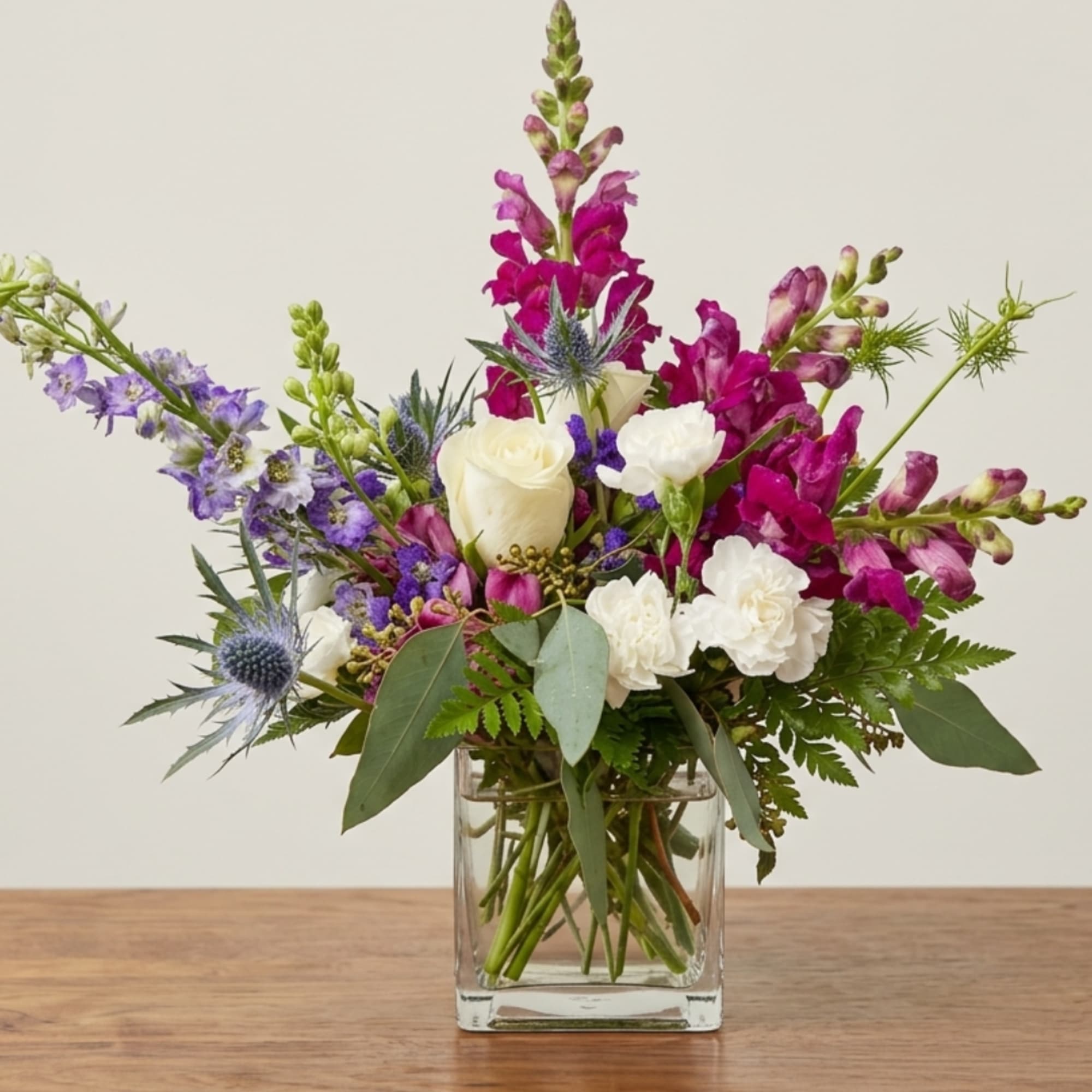 Mixed bouquet of purple and white flowers in a clear glass vase