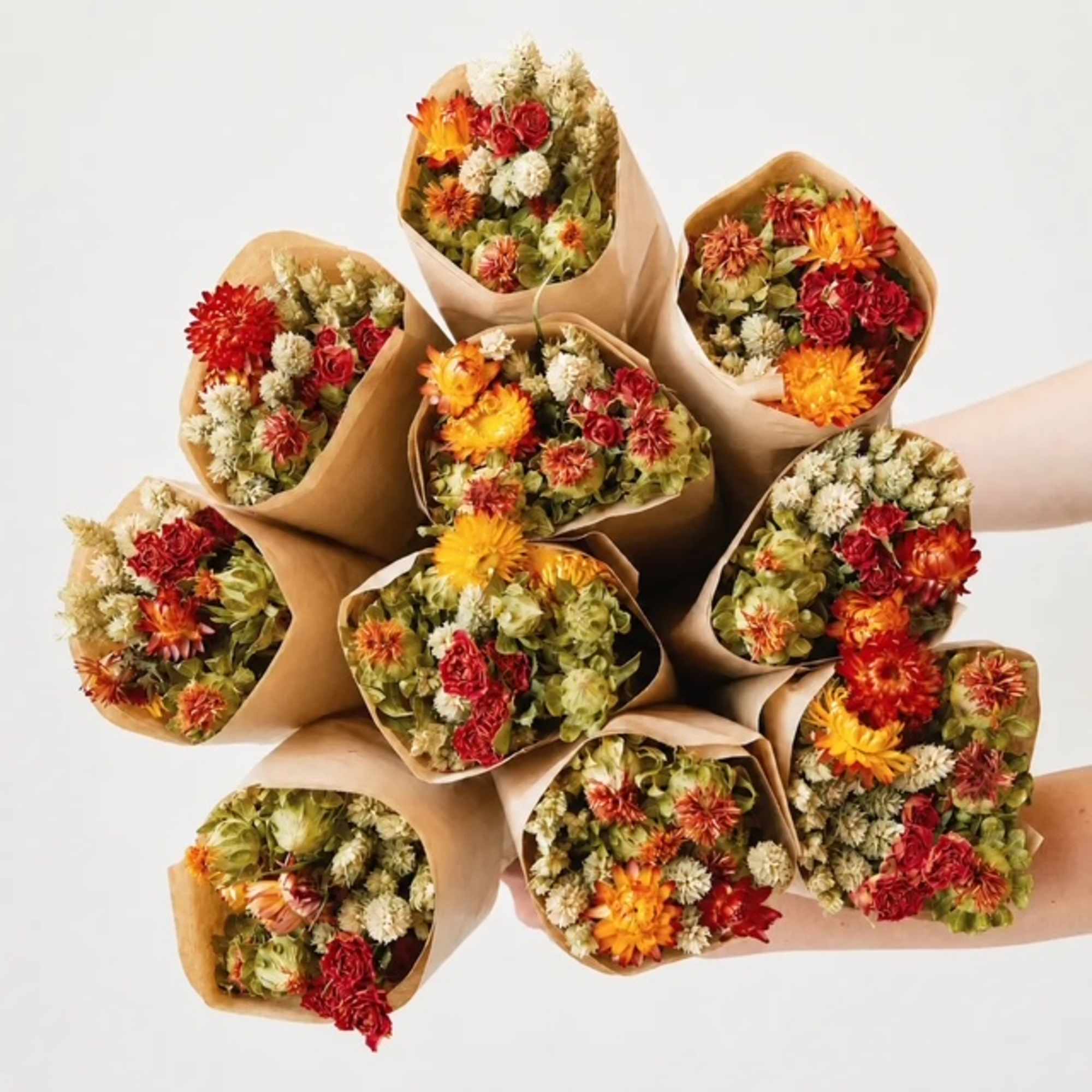 Several wrapped bouquets of red, orange, and cream flowers arranged together.