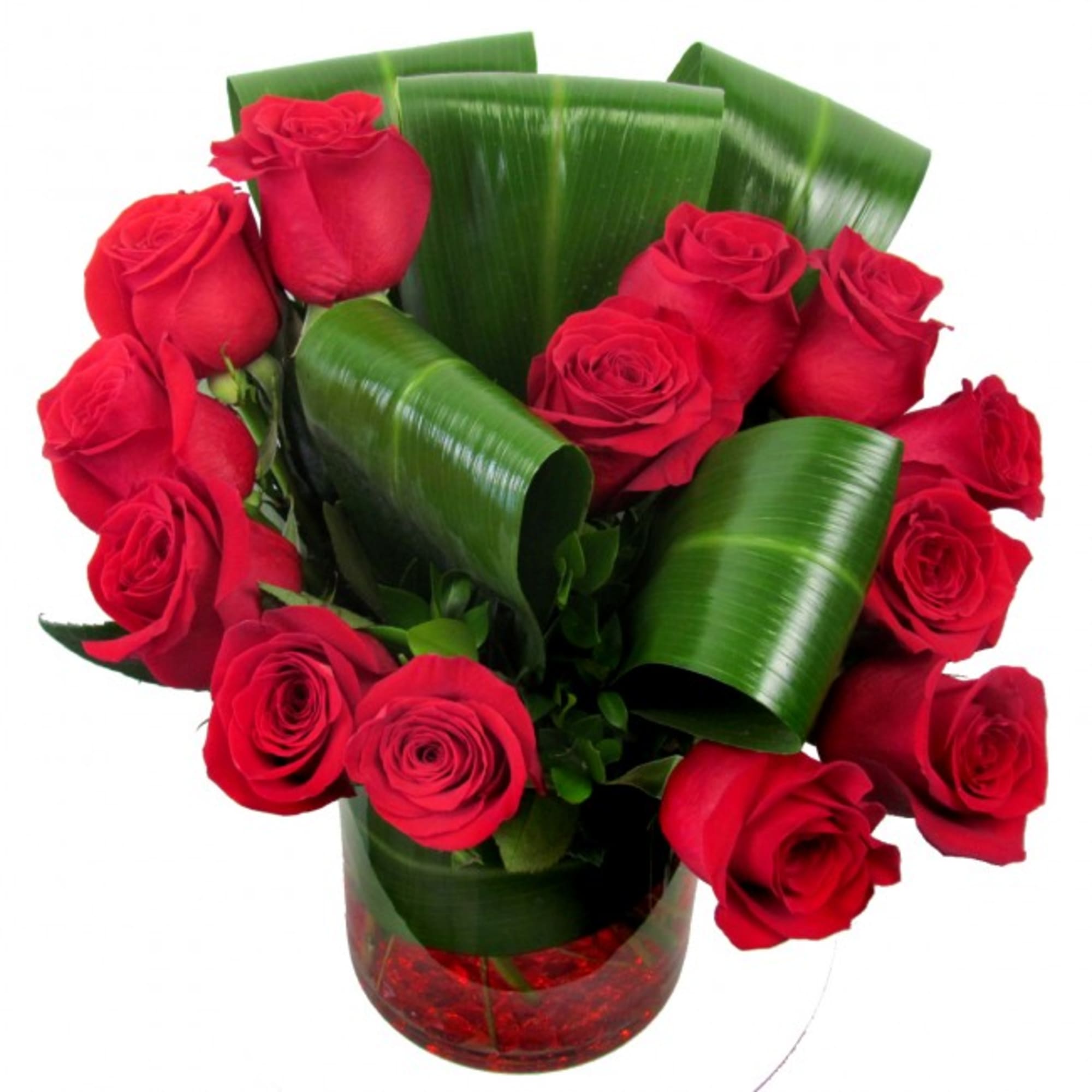 Red roses arranged in a clear vase with broad green leaves, photo 3 of 4