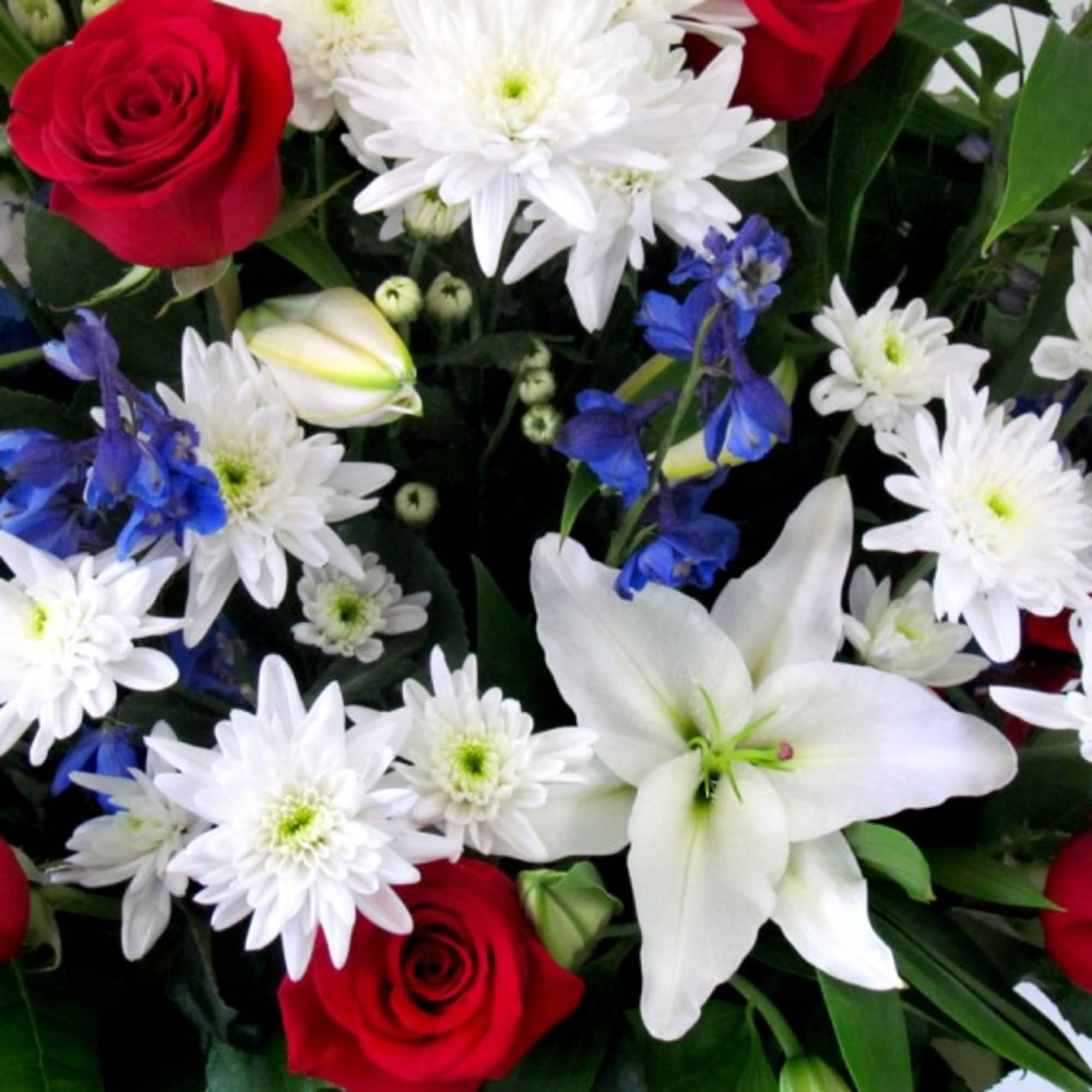 Bouquet of red roses, white lilies, and white daisies with blue flowers
