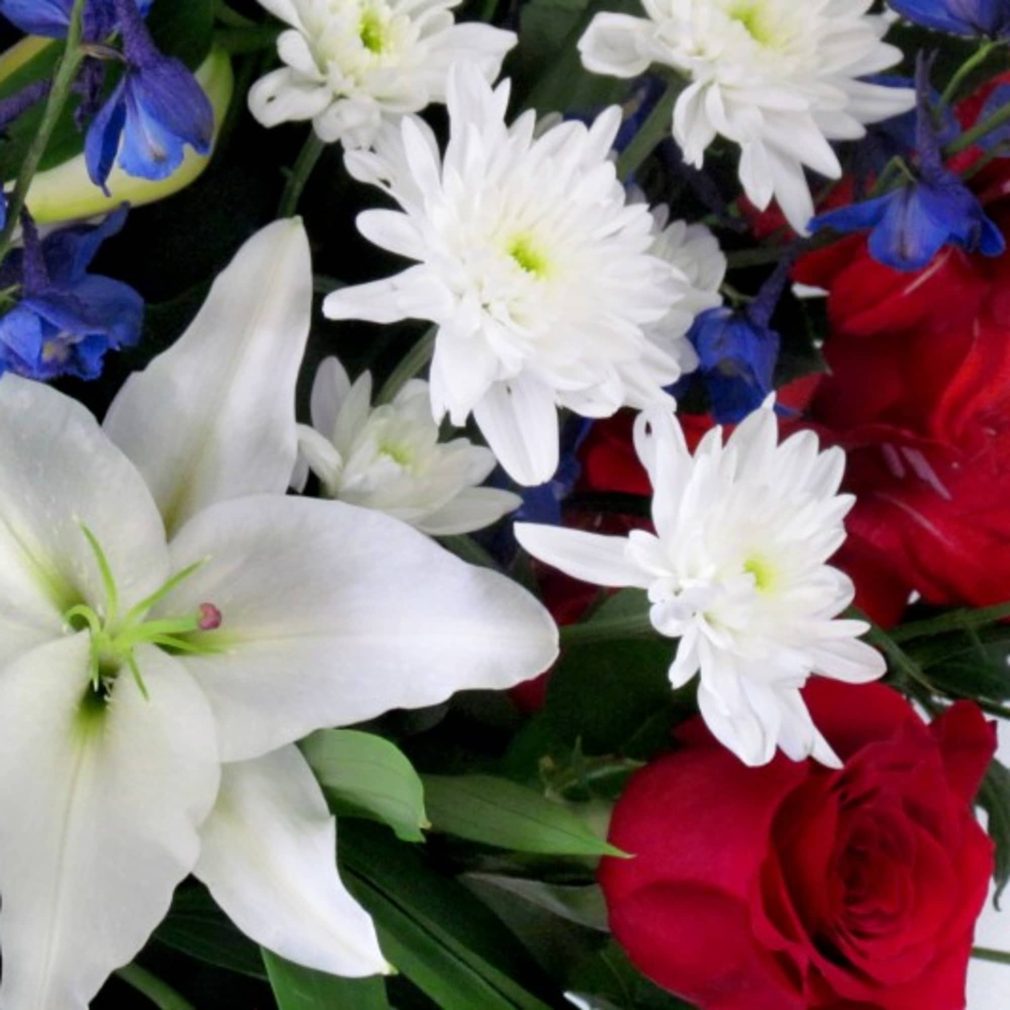 Bouquet of white lilies, red roses, and white daisies with blue flowers