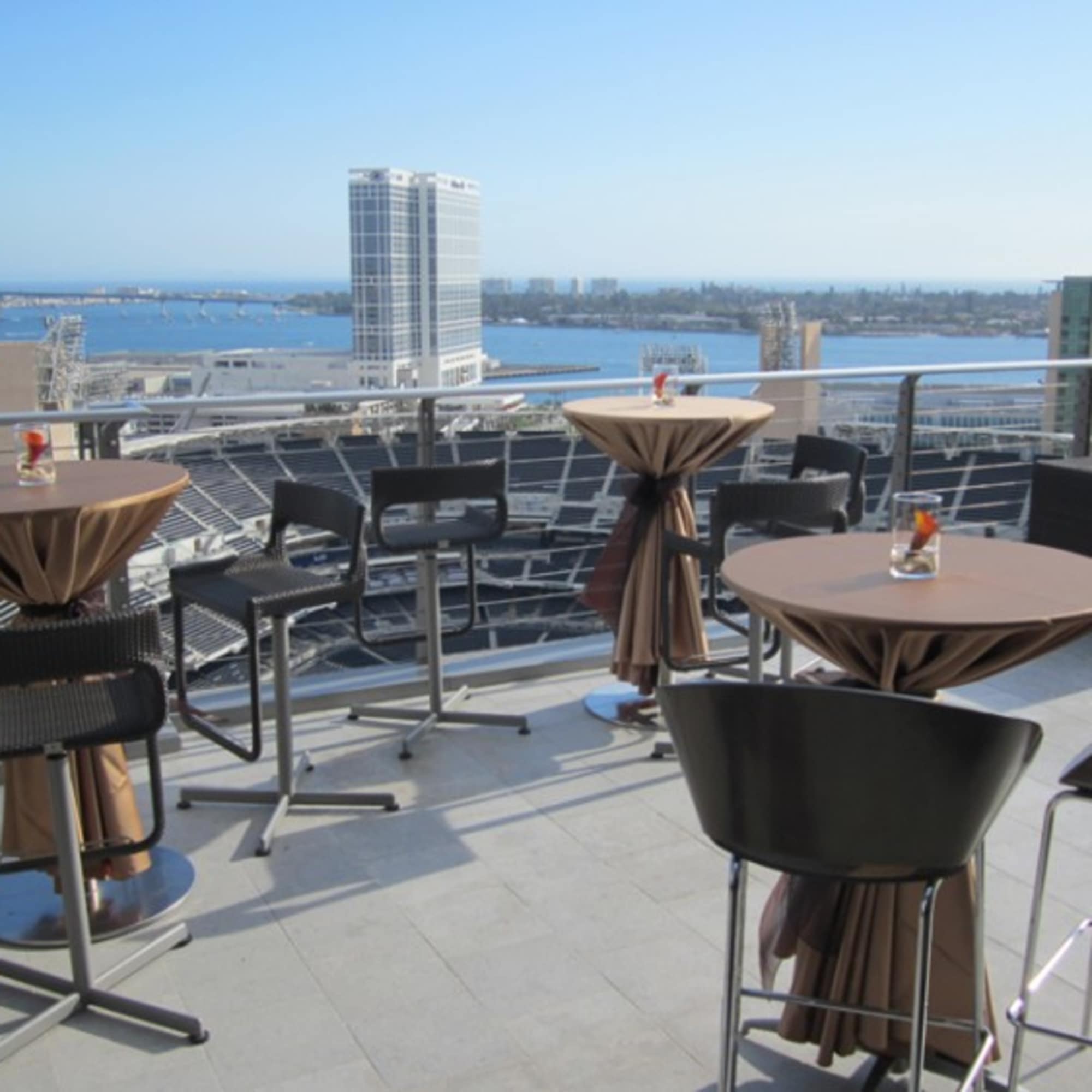 Rooftop patio with cocktail tables and chairs overlooking the water