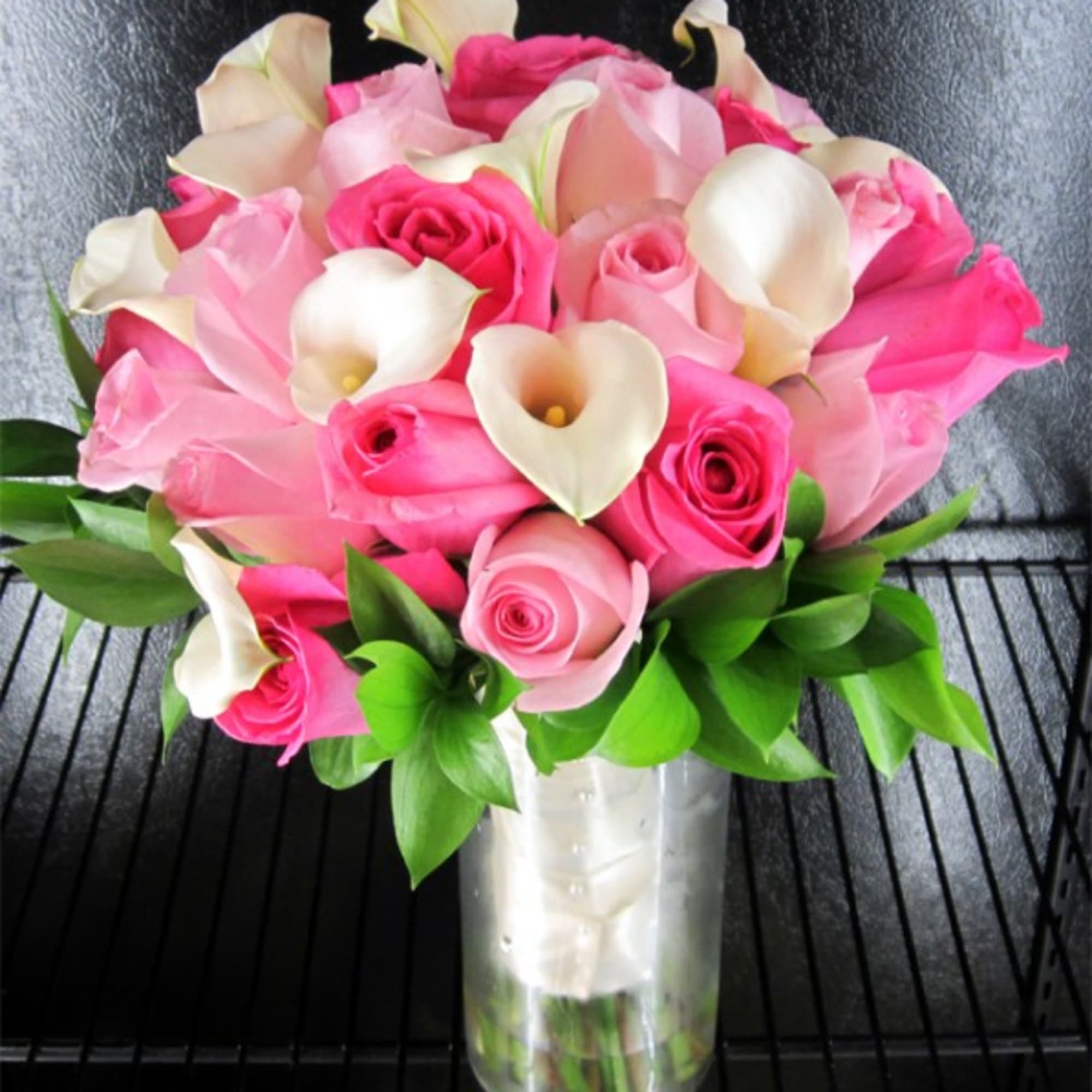 Pink roses and white calla lilies arranged in a clear glass vase