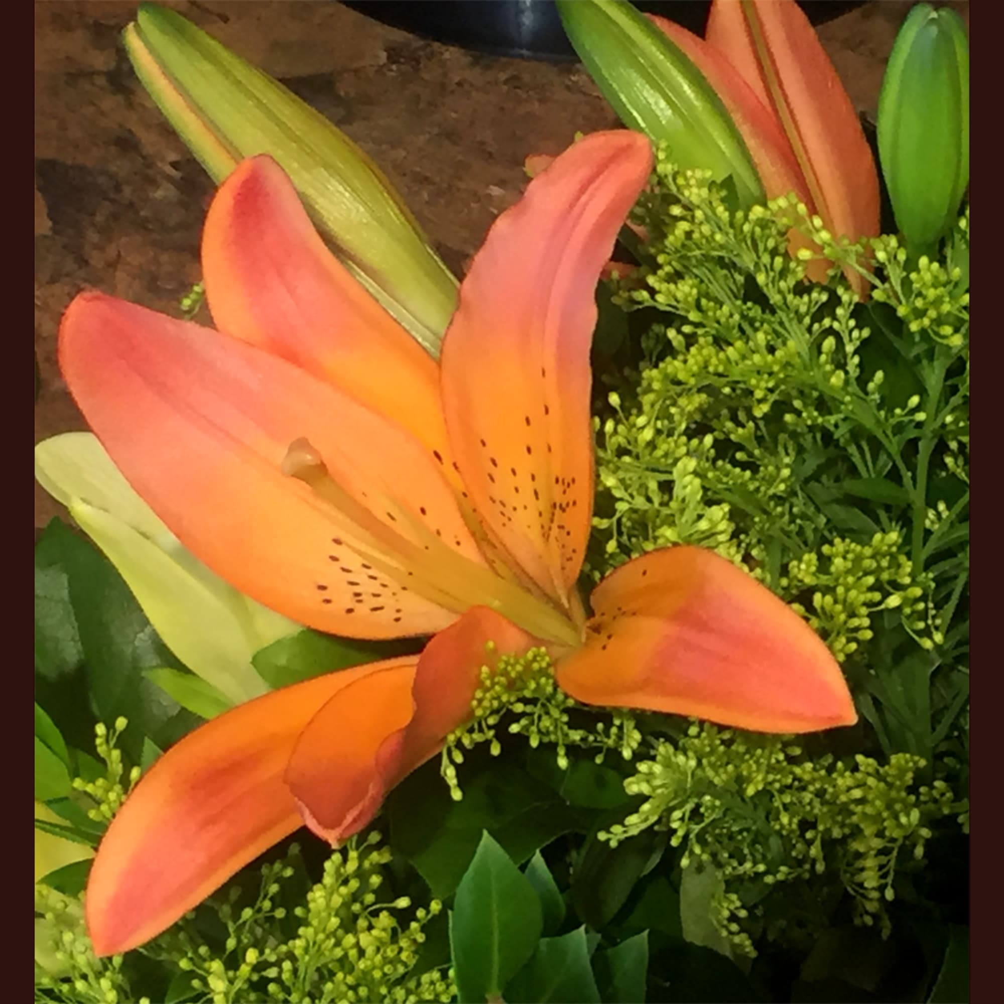 Orange lilies with green filler flowers and leaves