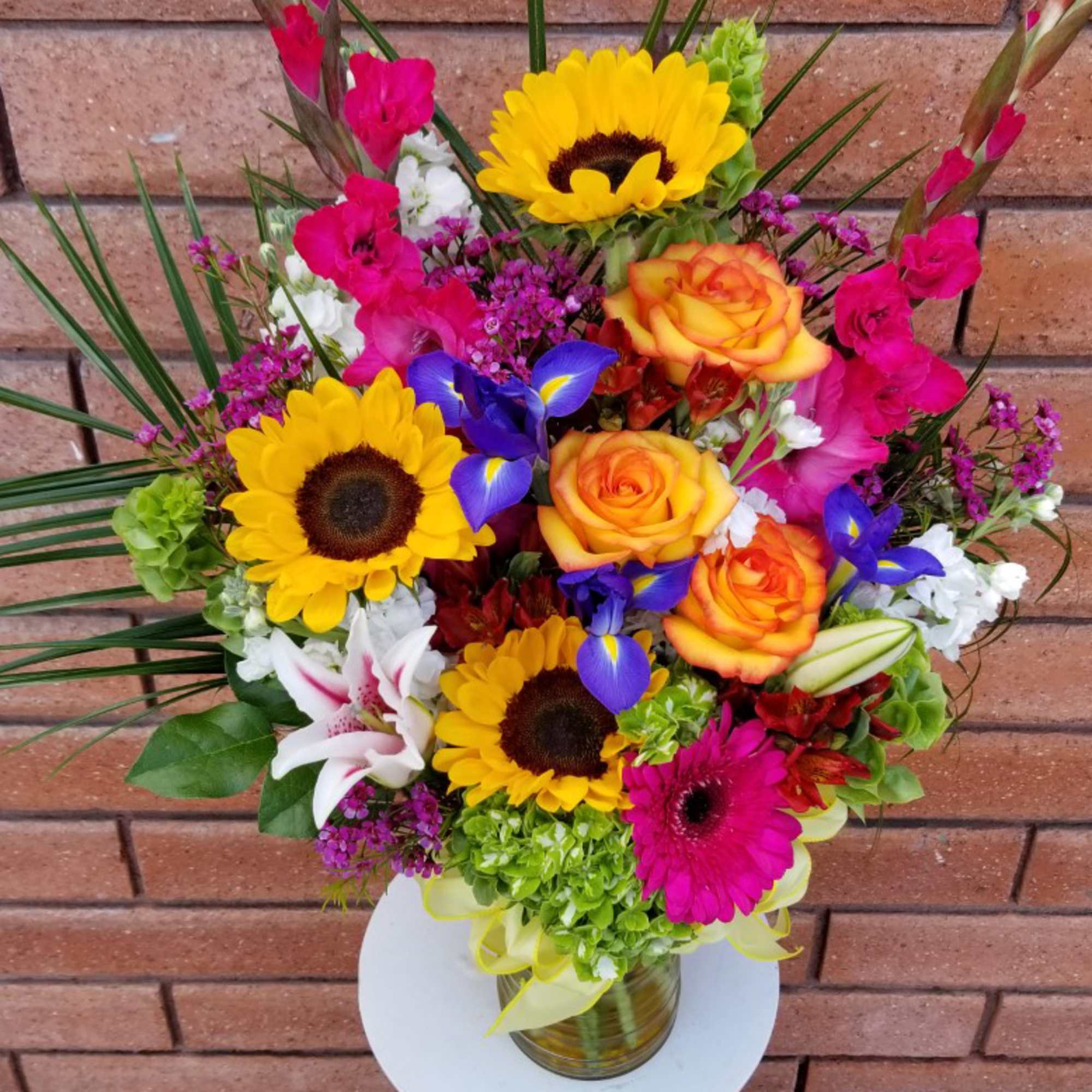 Colorful bouquet with sunflowers, roses, and irises in a glass vase