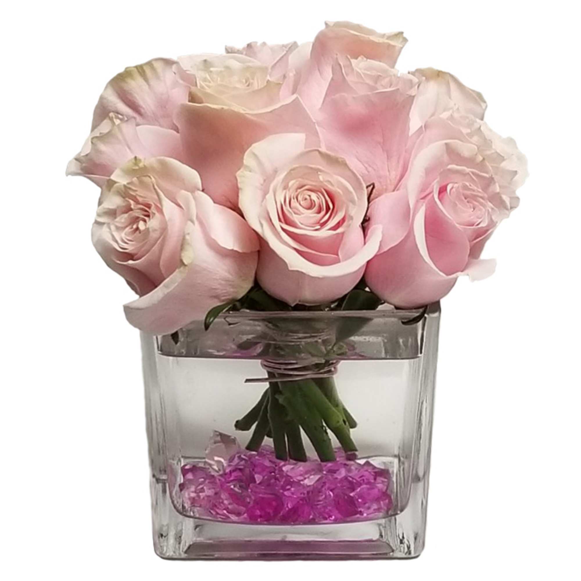 Pink roses arranged in a clear square vase with pink stones